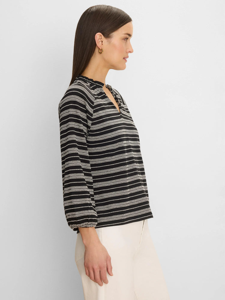 Black & white knit top with dotted horizontal stripes, ruffled high neck, V-slit, and long sleeves.