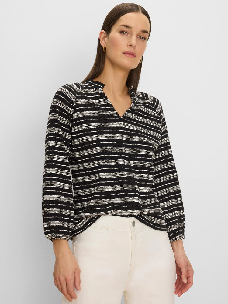 Black knit top with off-white dotted horizontal stripes, V-neck, gathered collar, and elastic cuffs.
