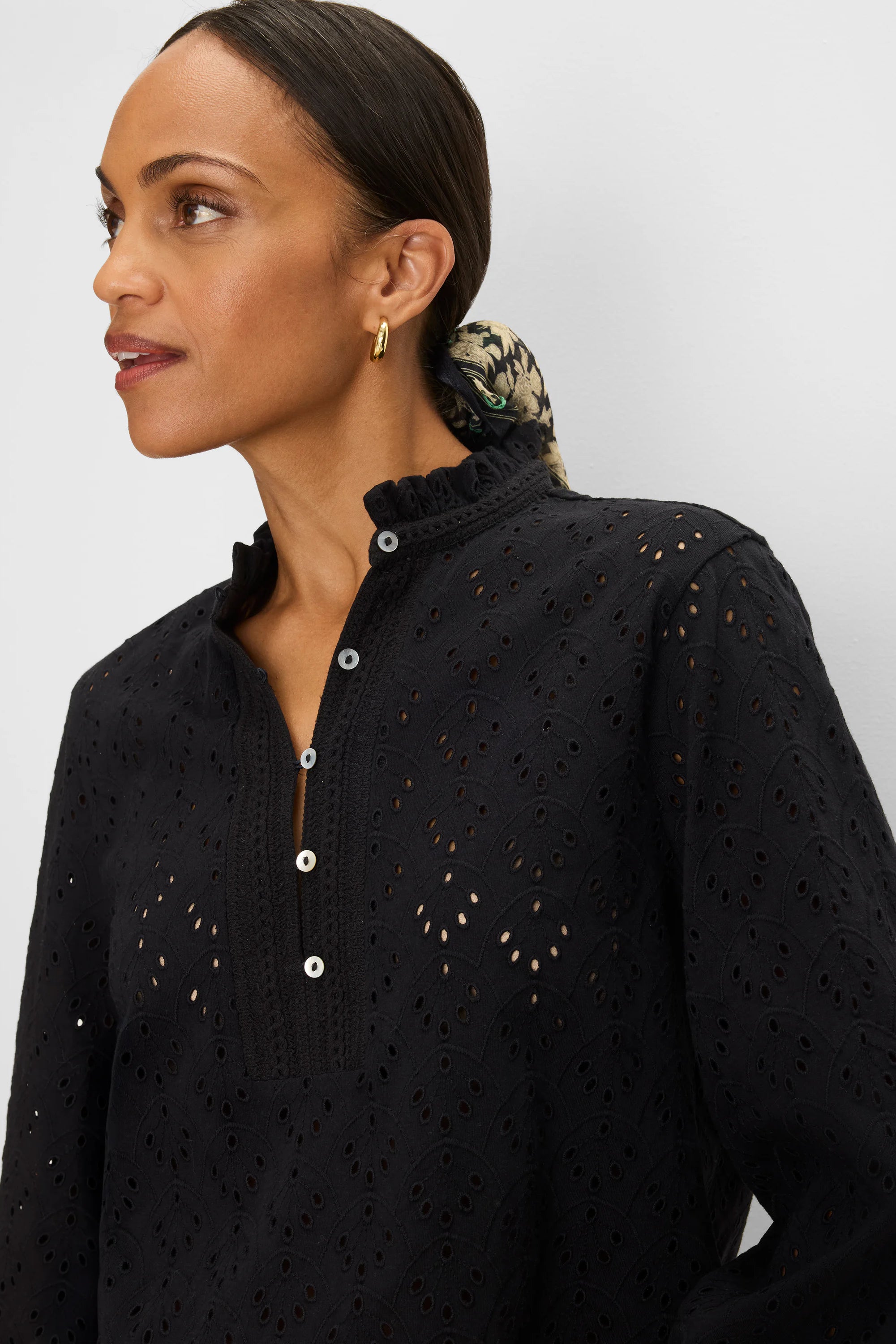Black knit top with all-over eyelet pattern, ruffle neck, and white button-down placket.
