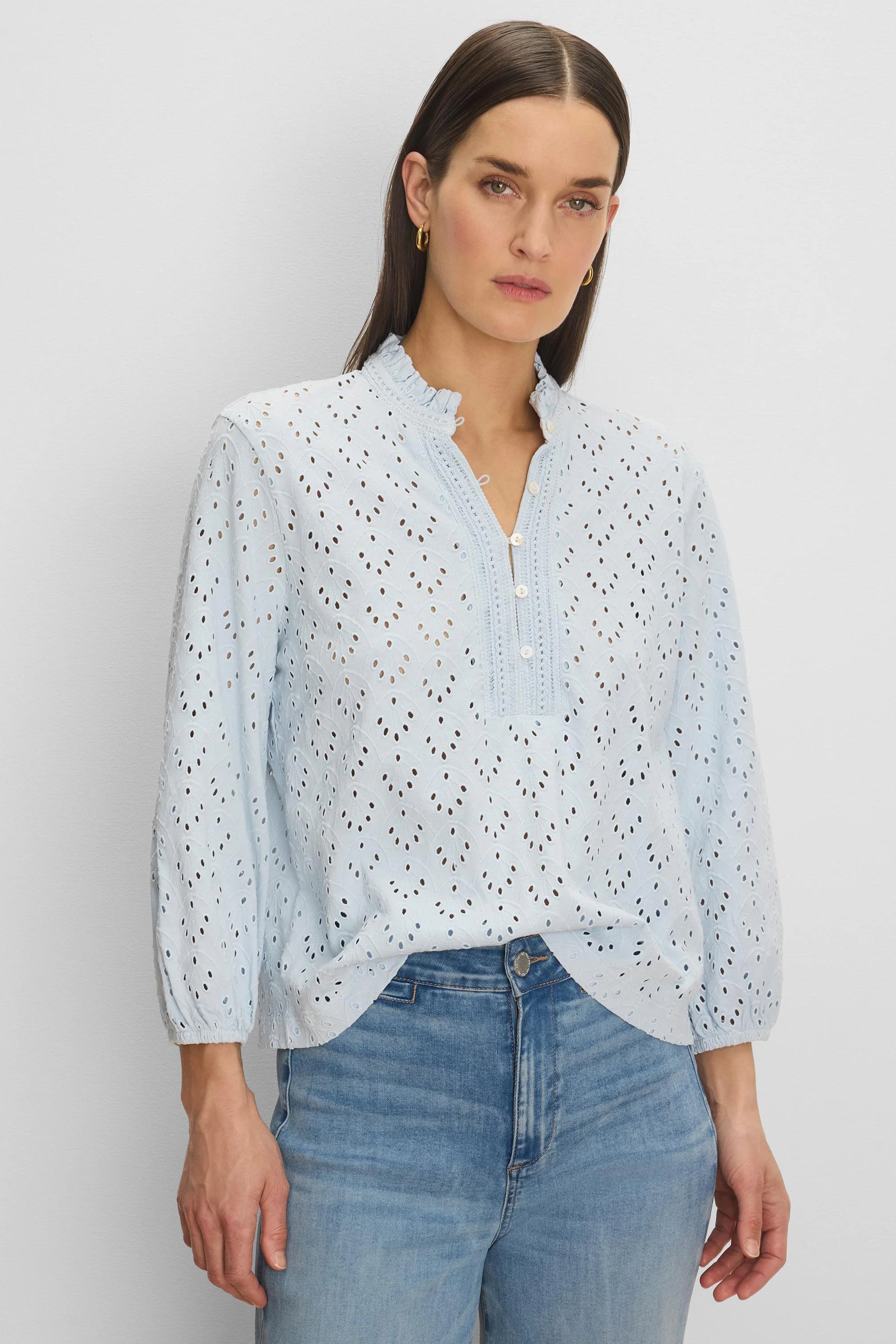 Light blue eyelet top with a ruffle neck, partial button placket, and long sleeves.