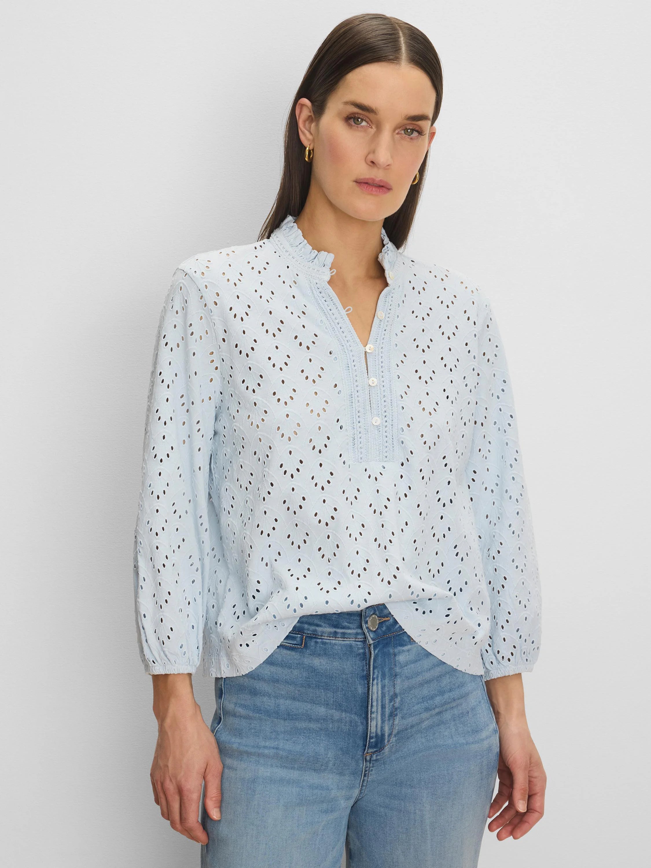 Light blue eyelet top with a ruffle neck, partial button placket, and long sleeves.