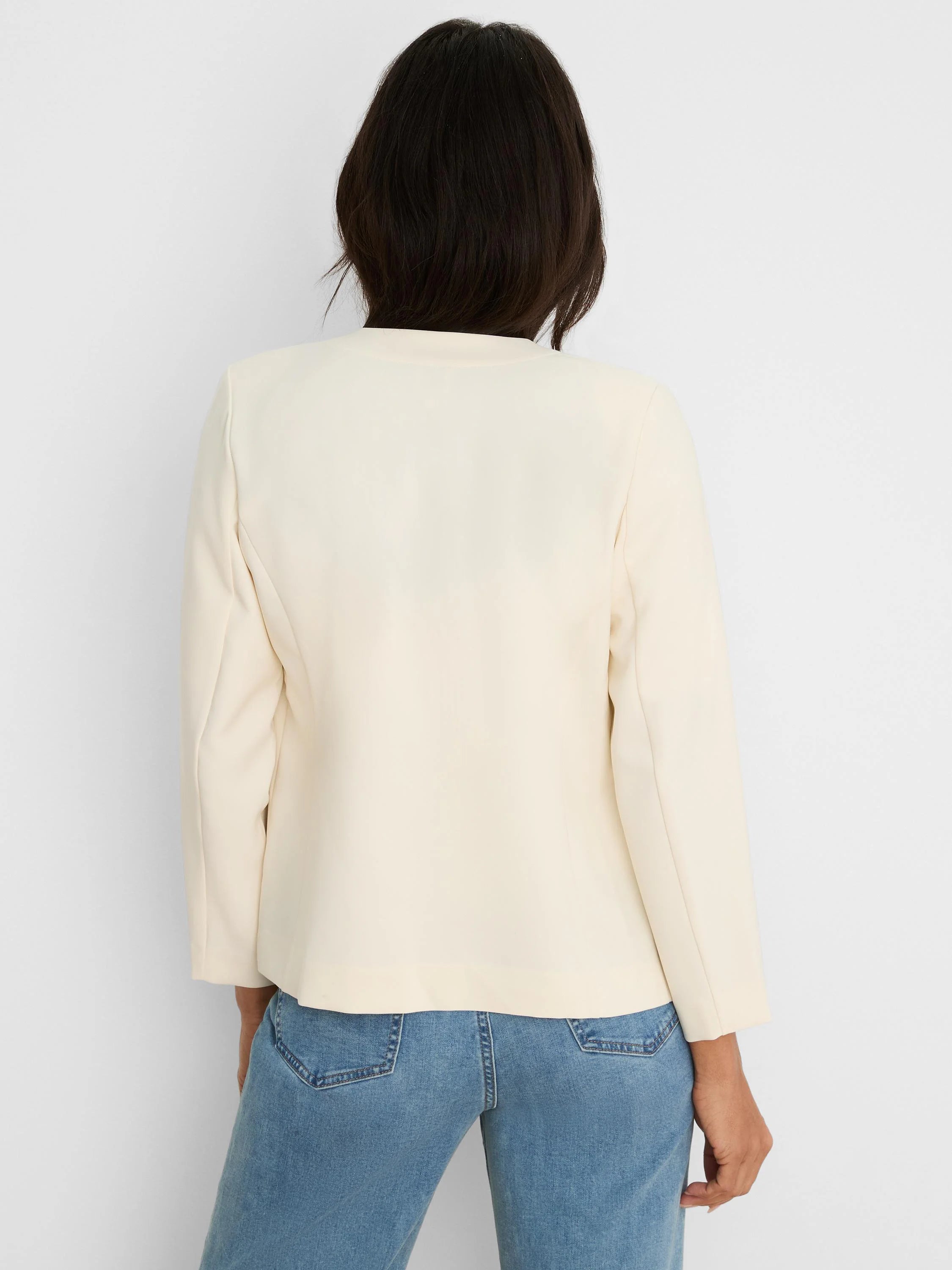 Rear view of a cream collarless jacket with 3/4 sleeves.