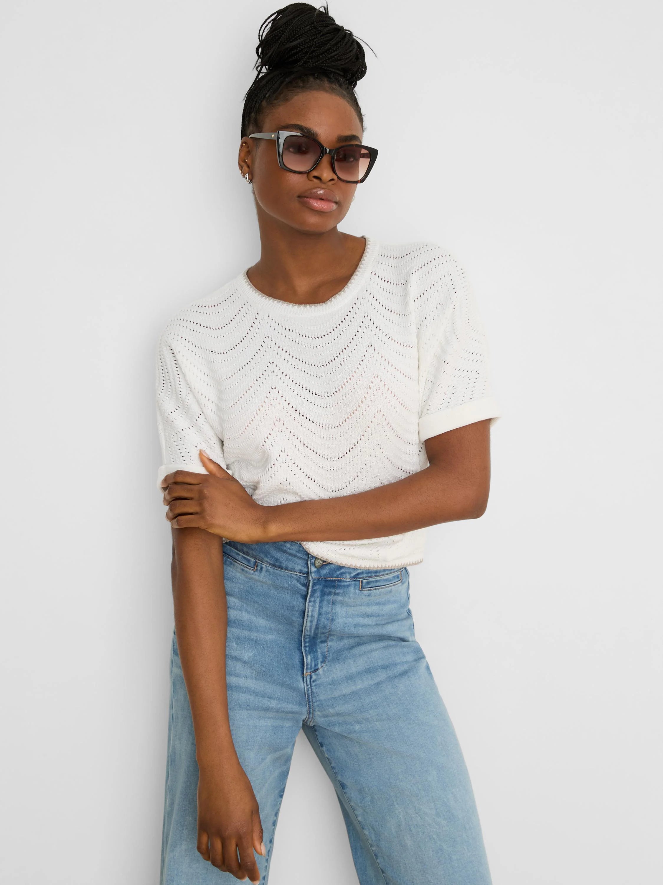 Off-white short-sleeve sweater with a wavy, open-knit swirl pattern and rolled cuffs.