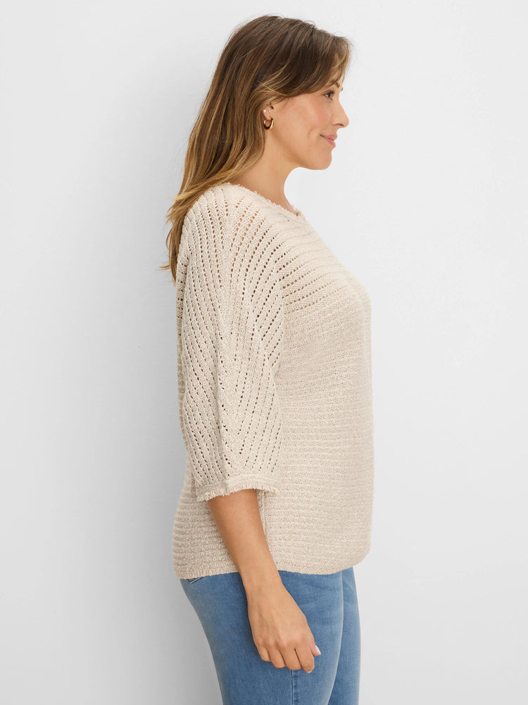 Cream-colored sweater with textured knit body and open-knit chevron 3/4 sleeves, featuring frayed cuffs.