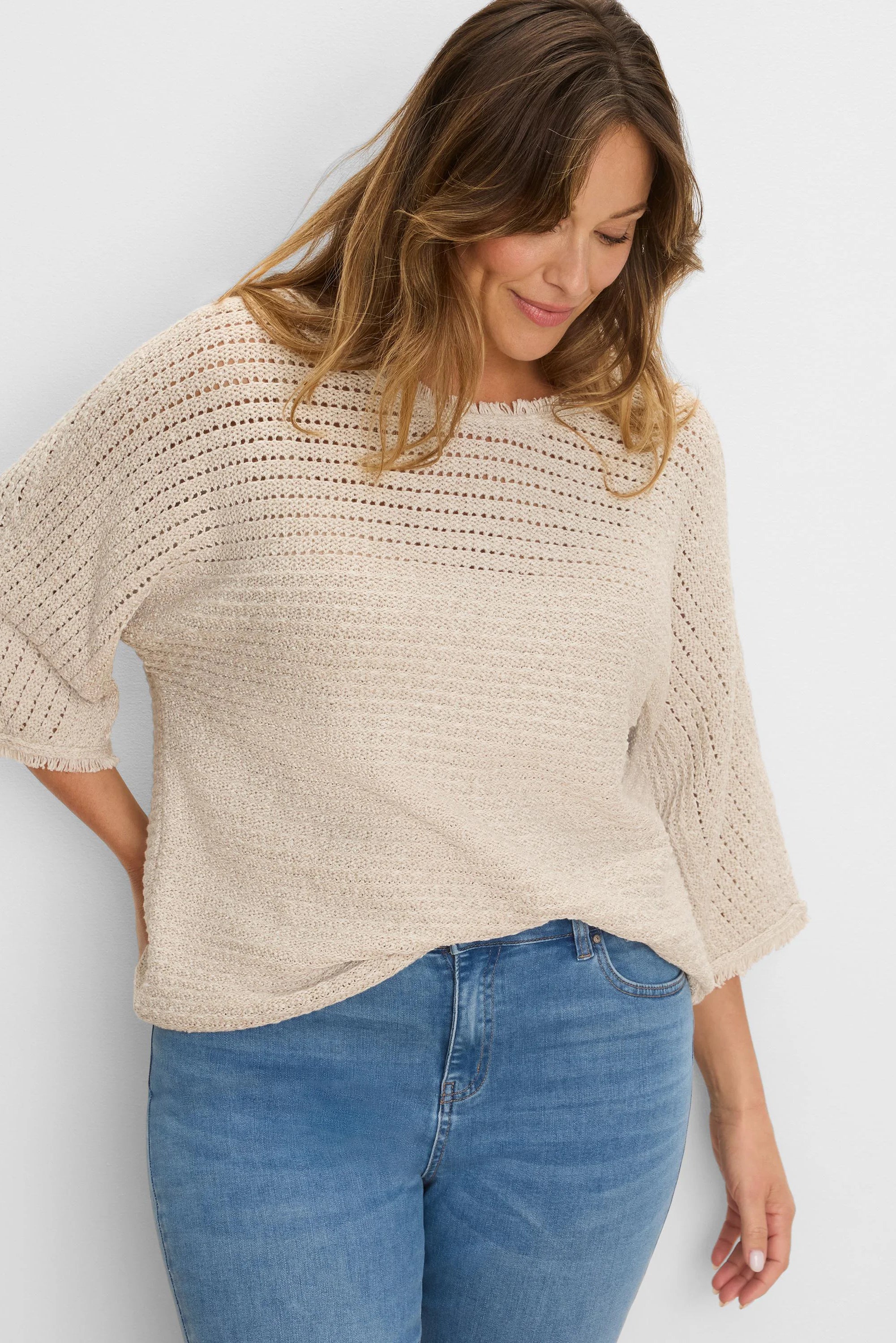 Light beige sweater with varied open-knit upper and dense body, 3/4 sleeves, and fringed edges.
