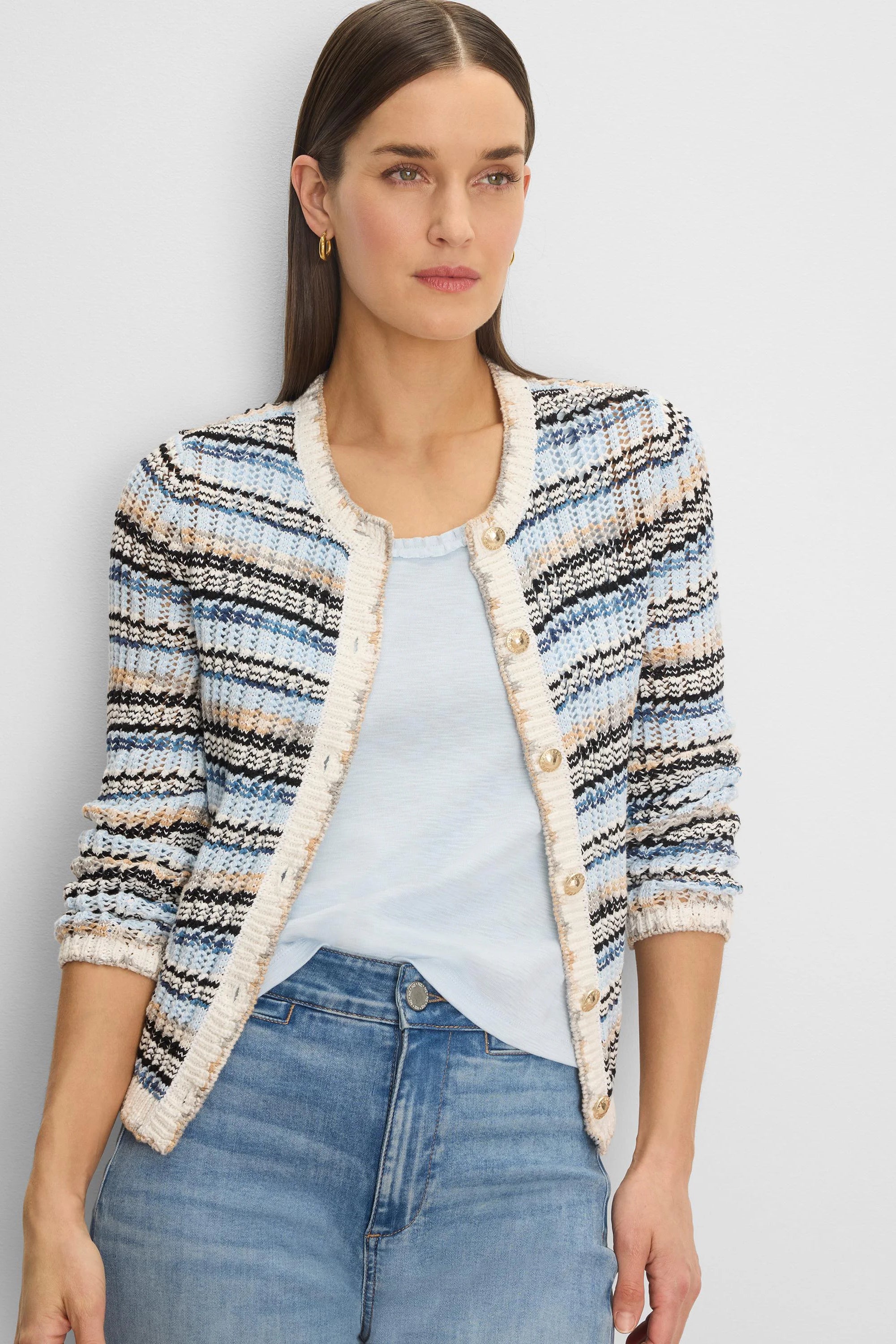 Wavy knit cardigan in shades of blue, black, tan, and white, with gold buttons and cream trim.