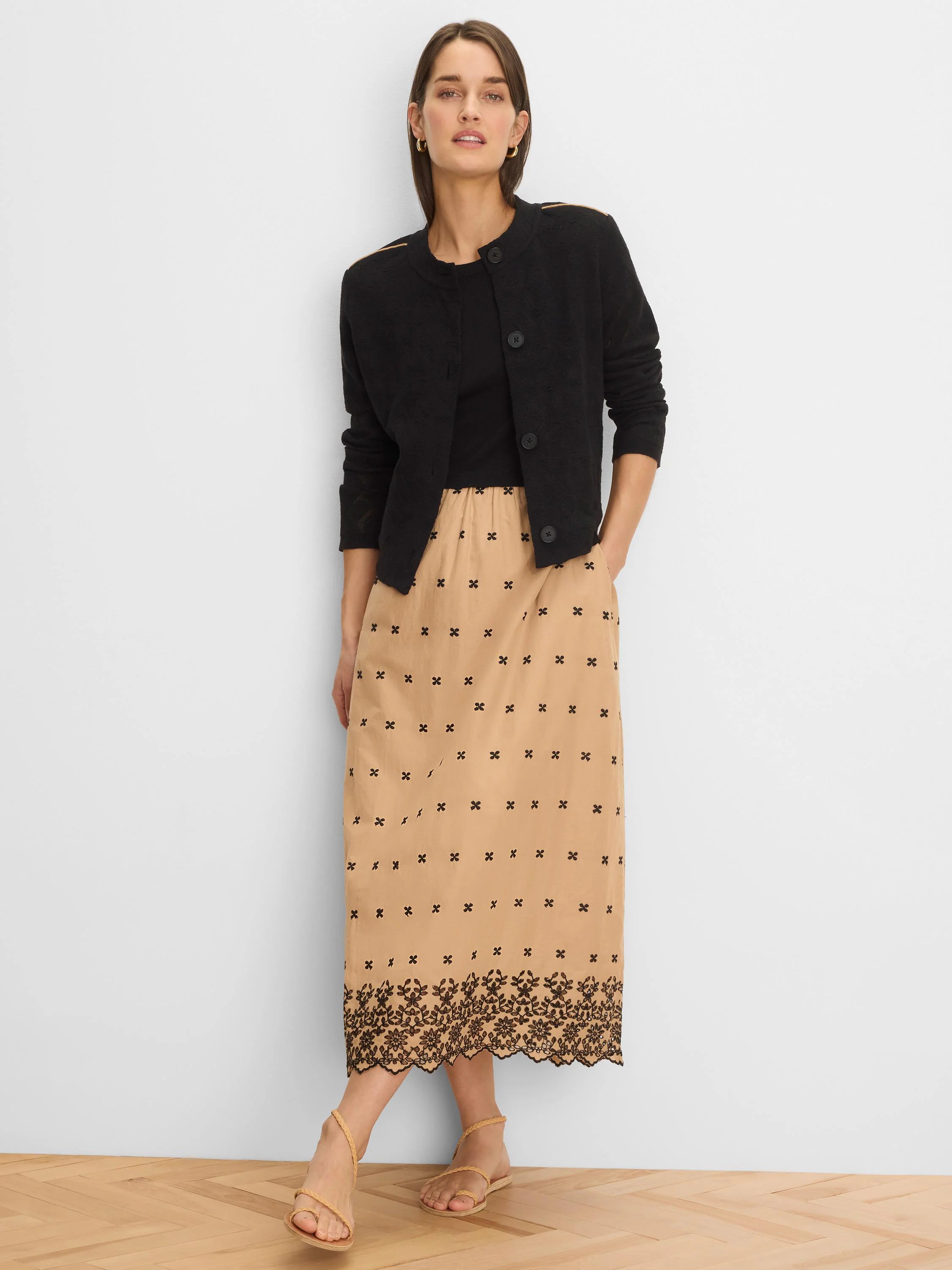 Black knit jacket with a subtle textured pattern, light tan piping on the shoulders, and dark front buttons.