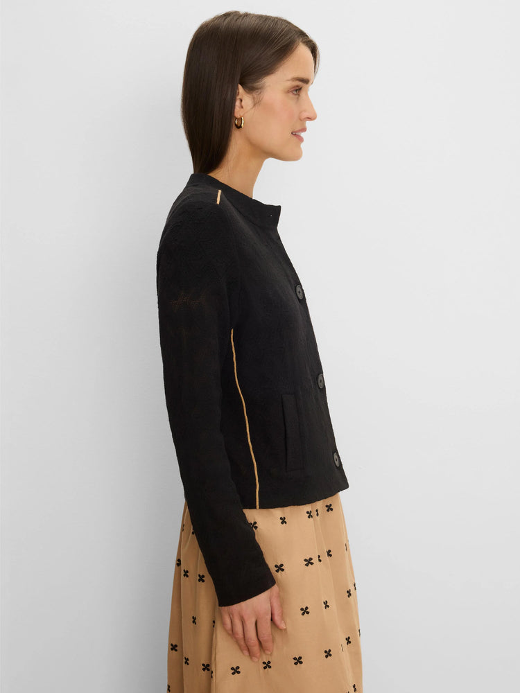 Black textured knit jacket with tan piping, collarless, button-front closure, and a visible patch pocket.