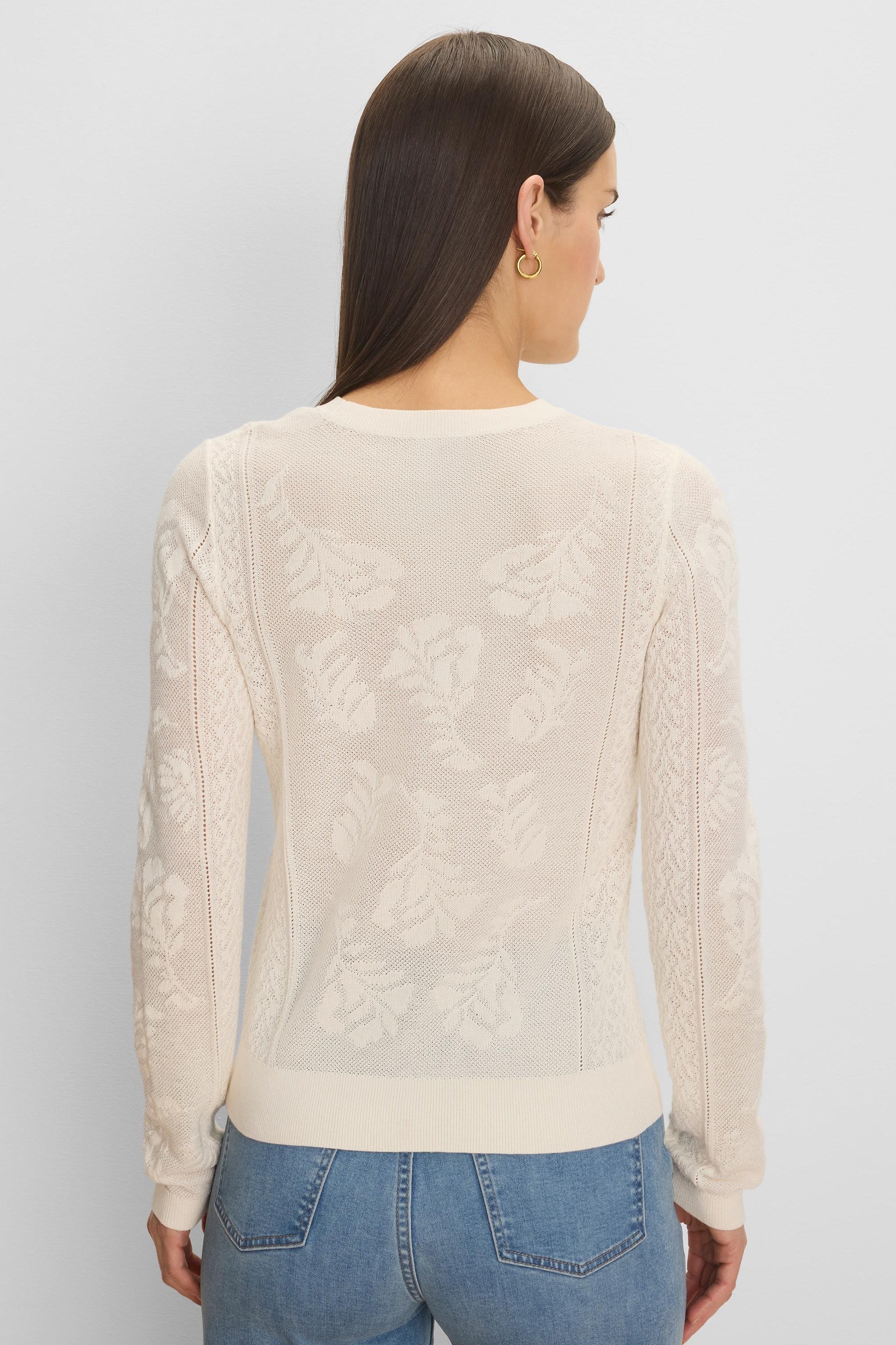 Cream jacquard lace knit sweater with an all-over floral pattern, long sleeves, and ribbed trim.