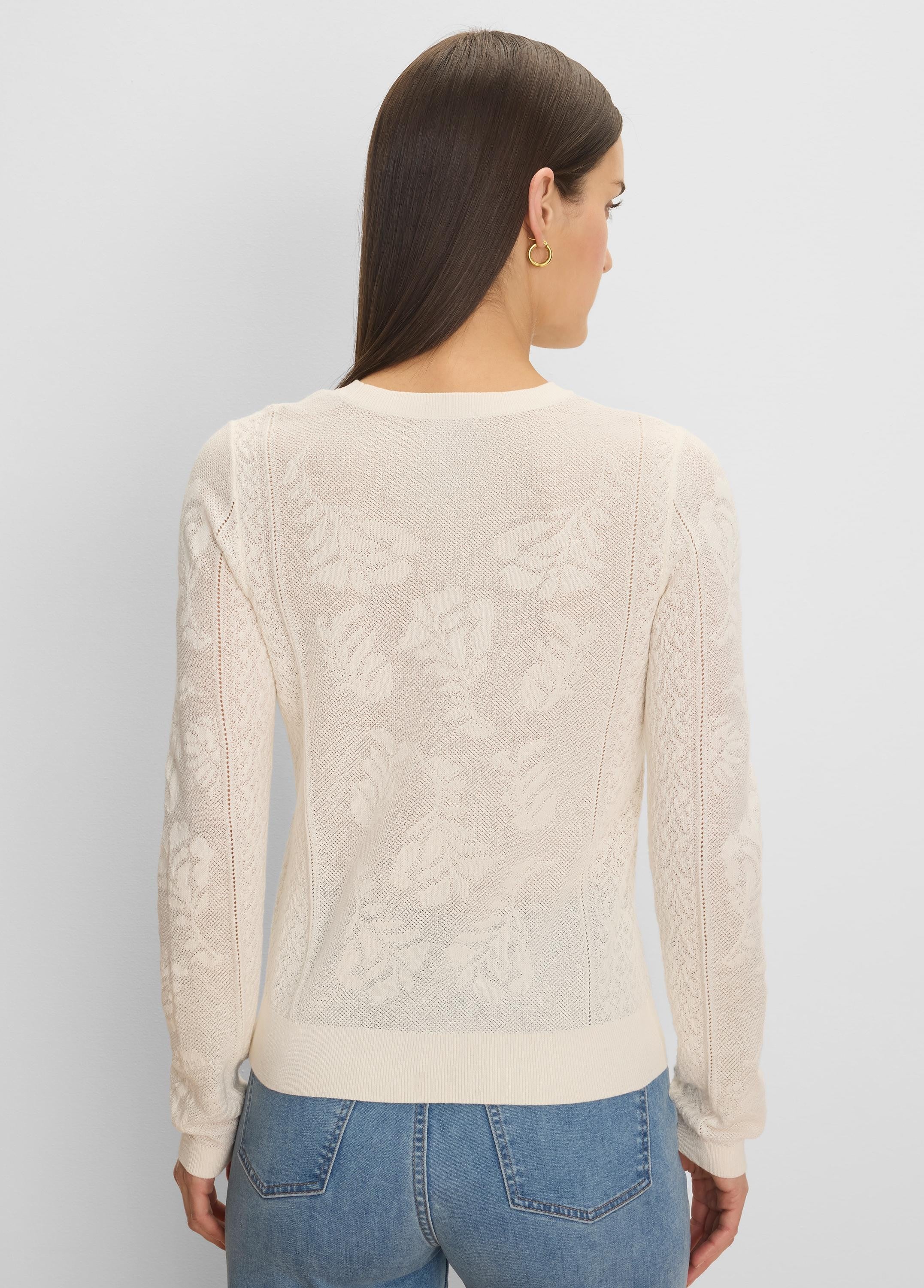 Cream jacquard lace knit sweater with an all-over floral pattern, long sleeves, and ribbed trim.