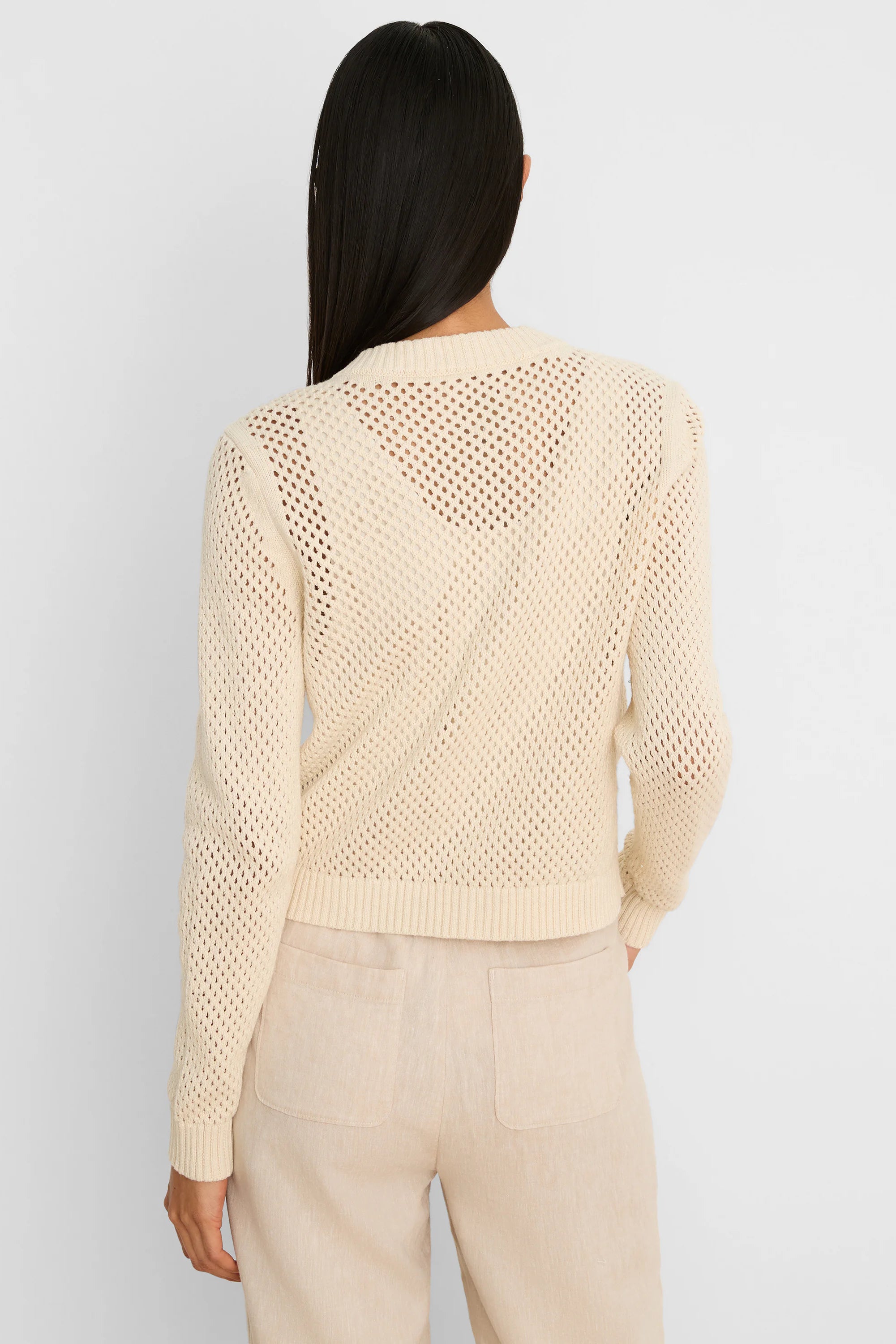 Cream open-knit cardigan shown from the back, featuring ribbed cuffs and hem.
