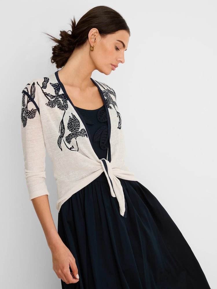 Cream open cardigan with dark navy floral print and trim, tied at the waist. It has 3/4 sleeves.