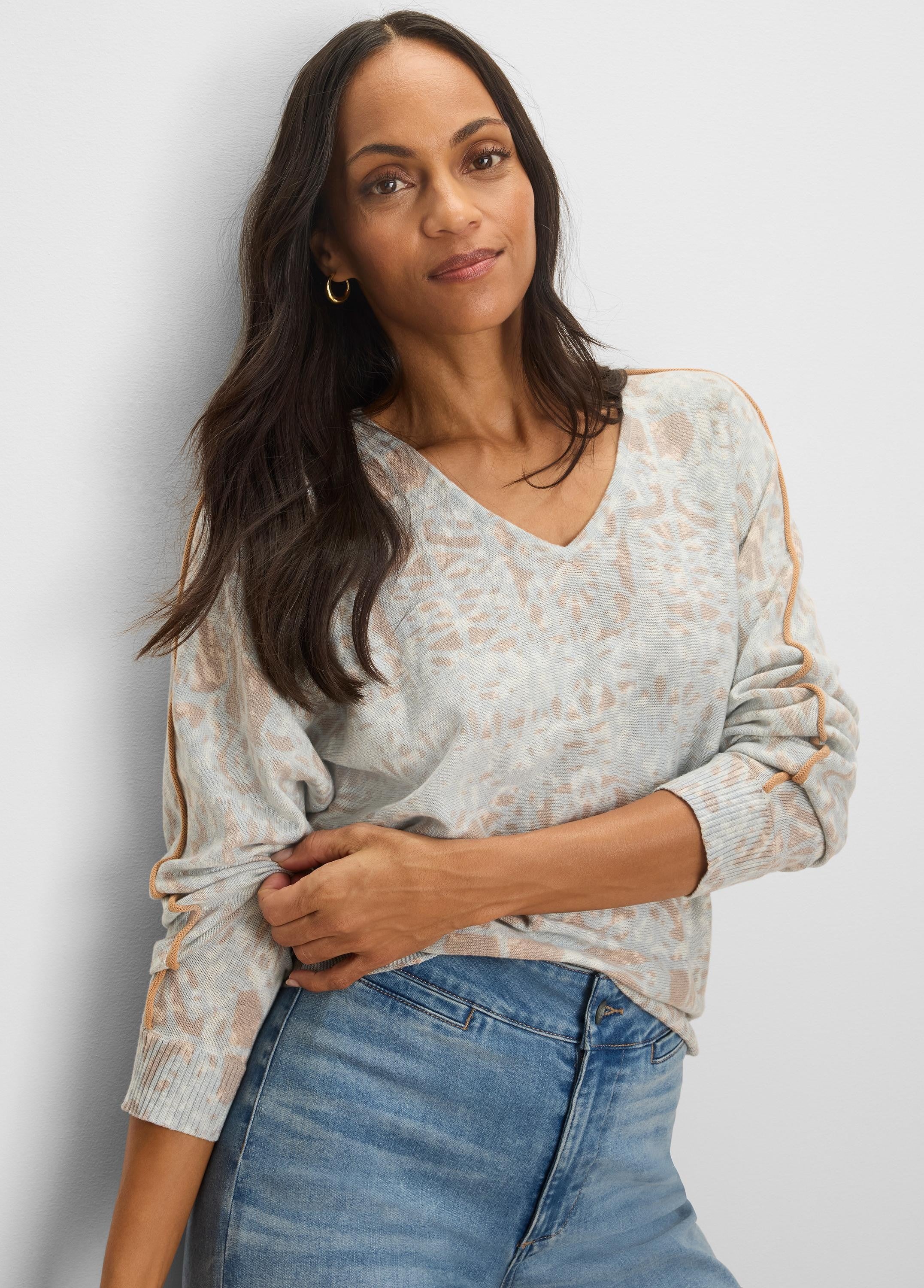 Light gray V-neck sweater with a tan abstract pattern and caramel tipping along the shoulder and sleeve seams.