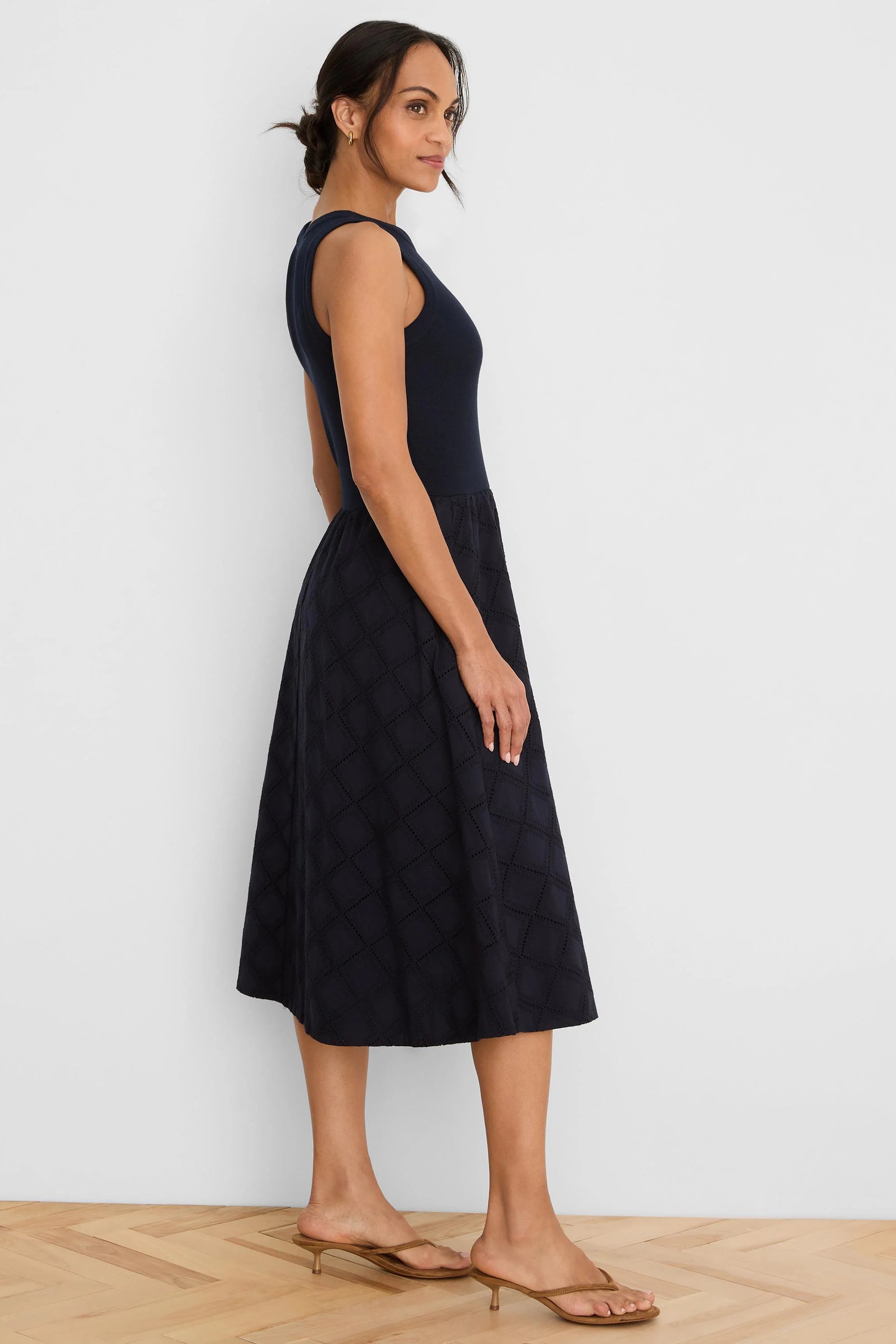 Navy blue sleeveless dress with a fitted top and a flared midi skirt featuring a diamond eyelet pattern.