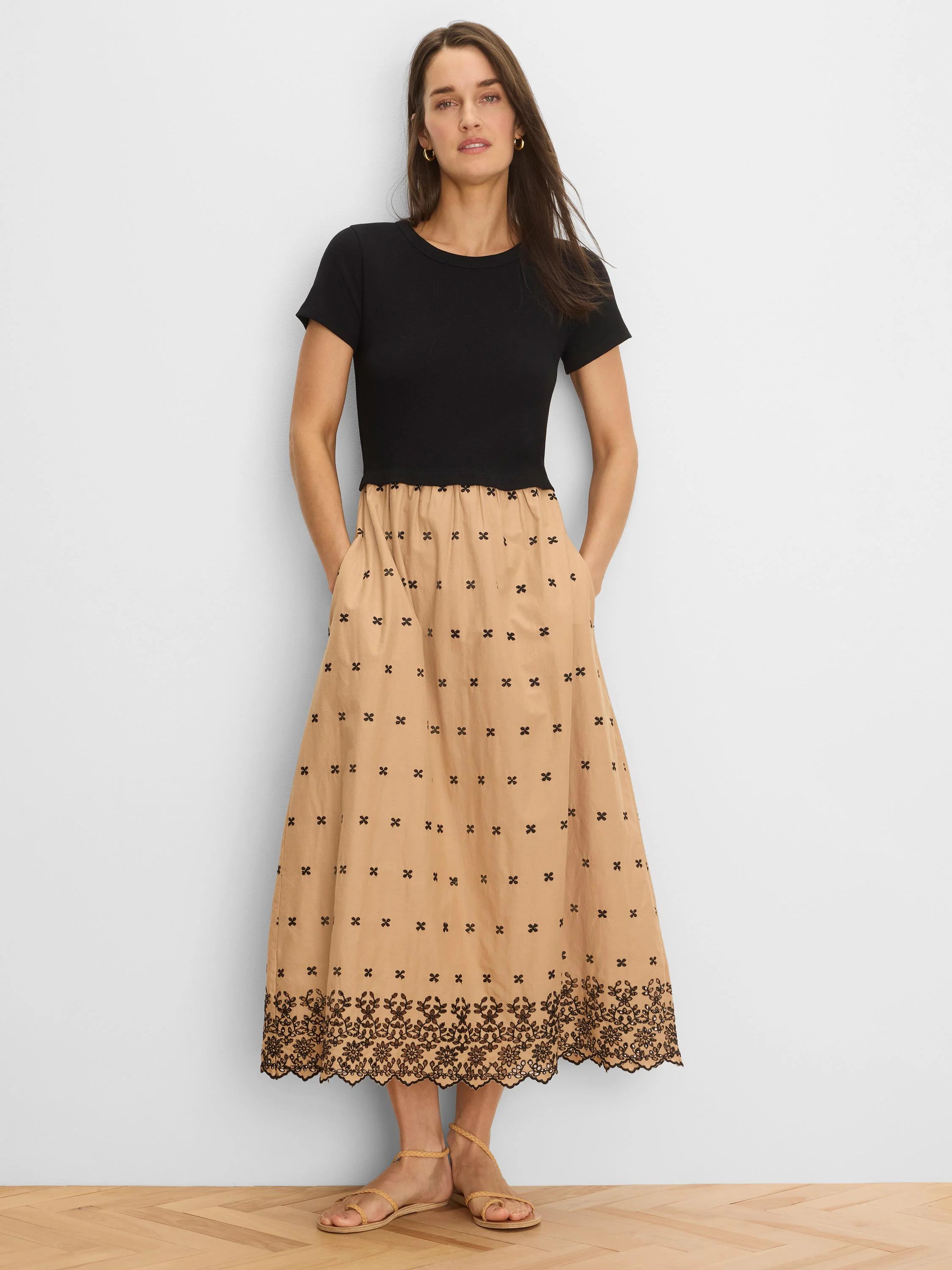 Black top, tan embroidered midi dress with scattered motifs and a detailed floral border.