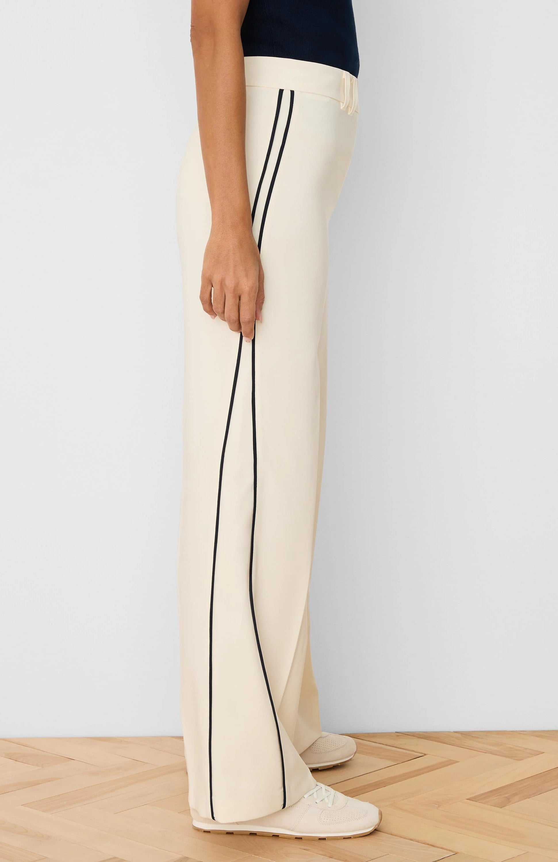 Cream wide-leg pants with dark vertical piping down the sides.