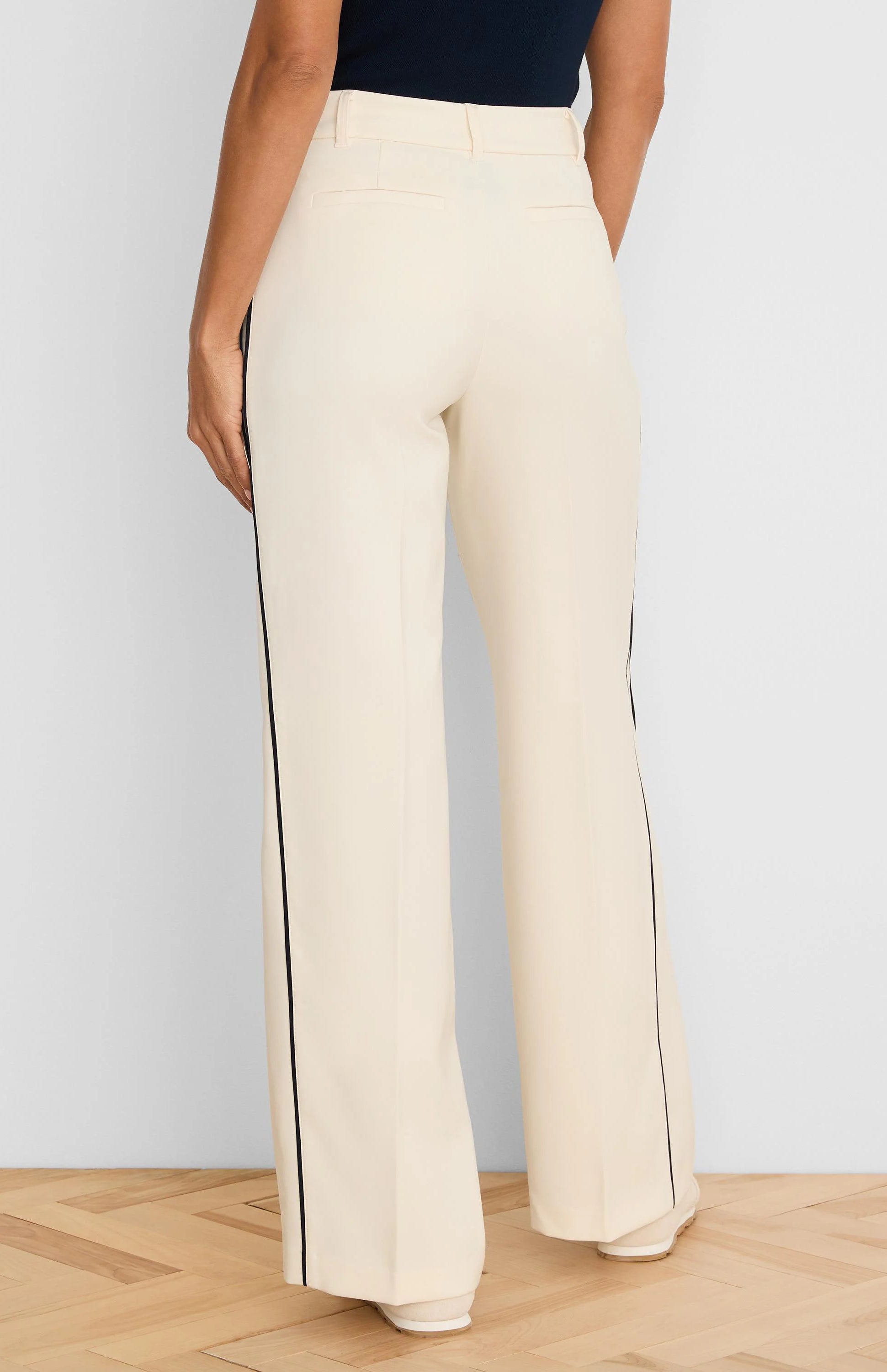 Cream wide-leg pants with navy vertical piping down the outer seams. Model shown from the back.