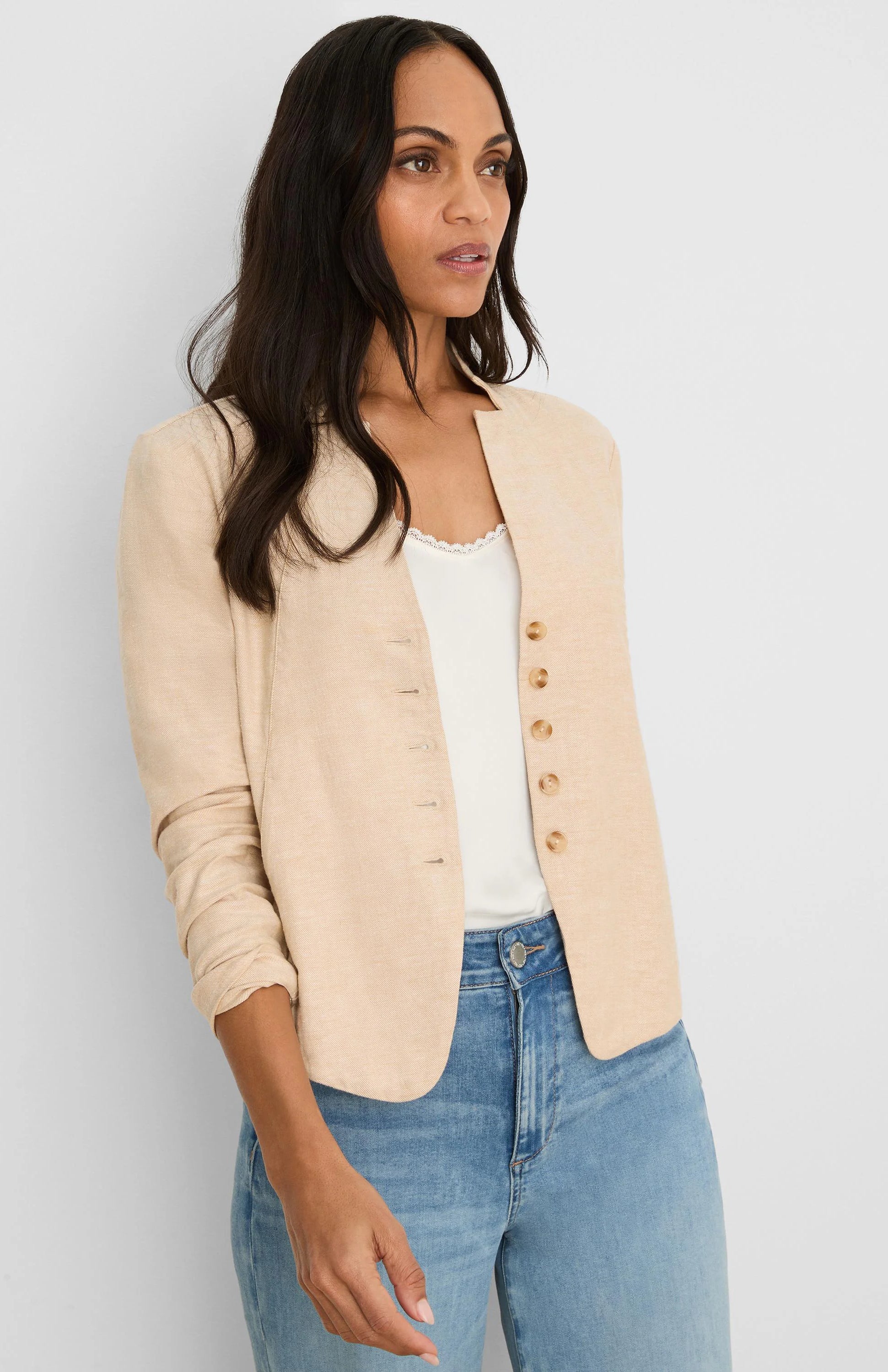 Beige stretch linen jacket, collarless, with a single row of small brown buttons and rolled sleeves.