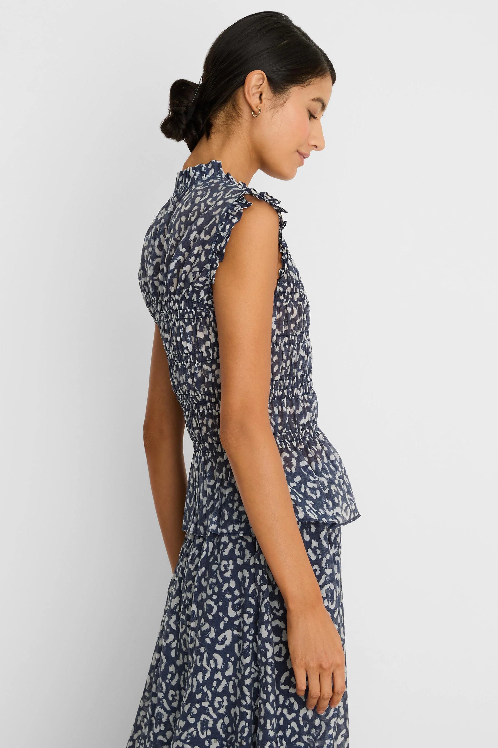 Navy blue top with light leopard sketch print, smocked waist, ruffled neck, sleeveless, and peplum hem.