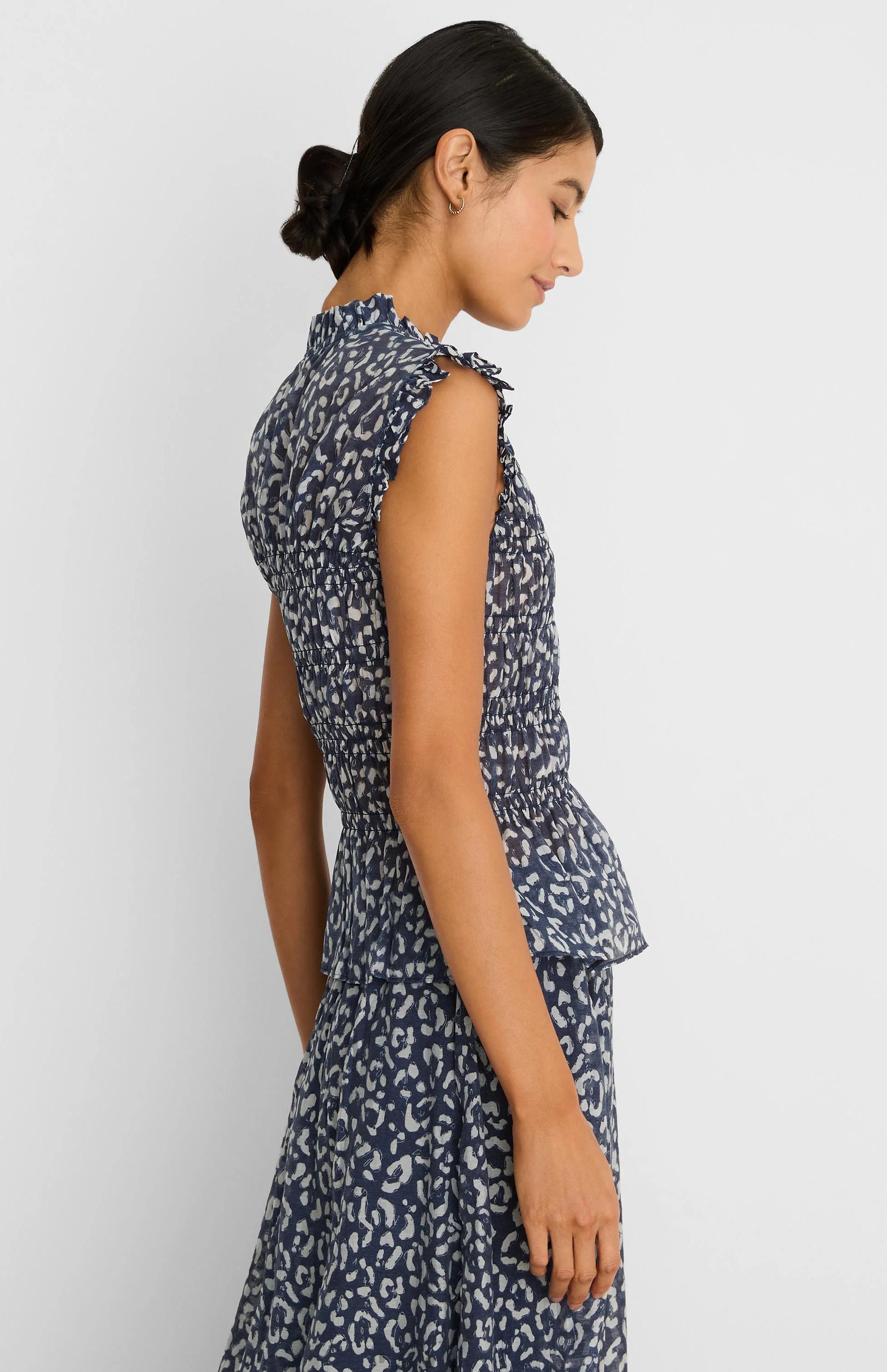 Navy blue top with light leopard sketch print, smocked waist, ruffled neck, sleeveless, and peplum hem.