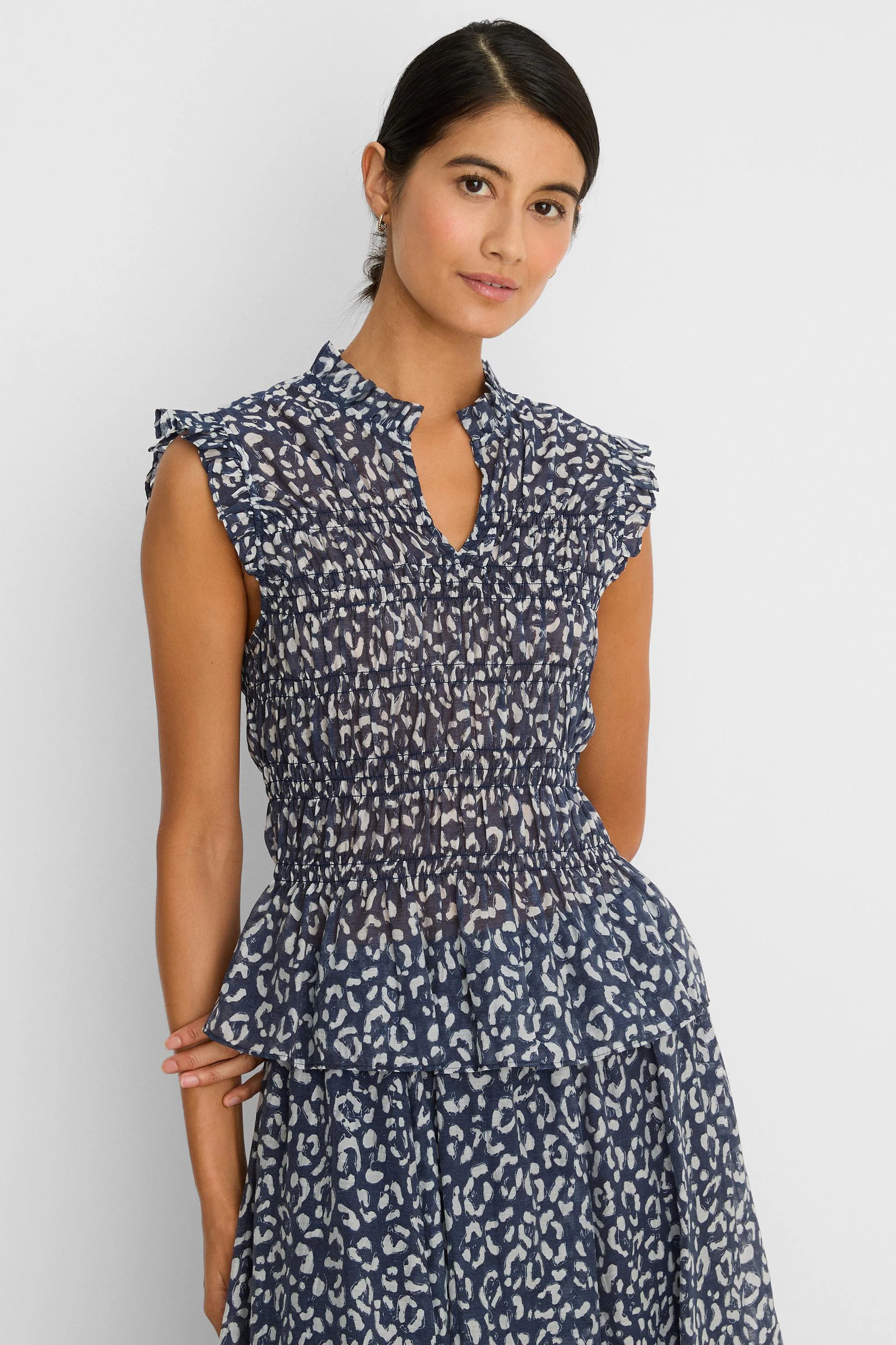 Navy and off-white leopard sketch smocked top with ruffled cap sleeves, stand collar with V-neck, and tiered hem.