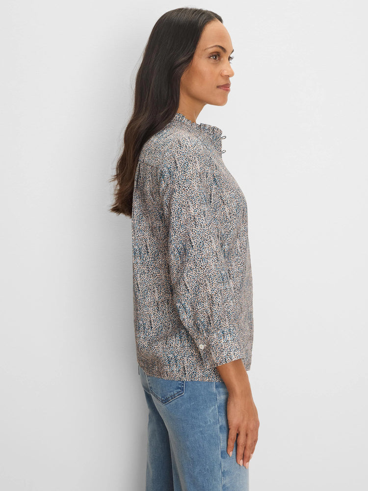 Light top, long sleeves, pale blue, tan & black speckled pattern, ruffled high neck.