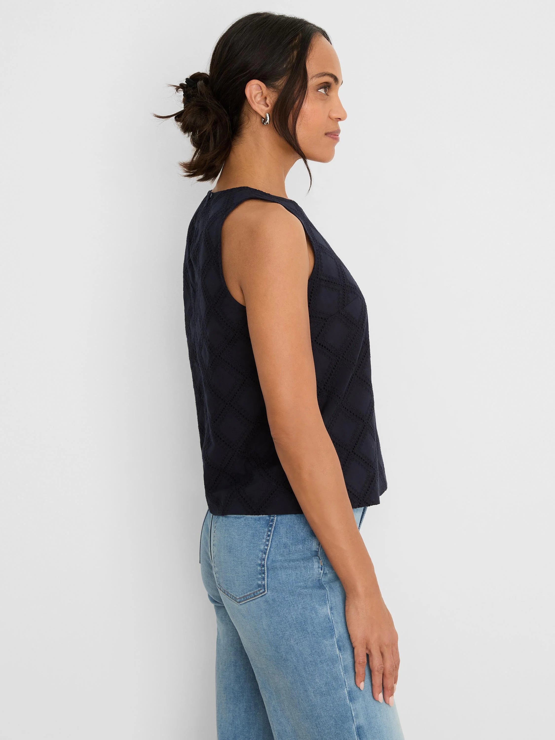 Navy blue sleeveless top with diamond eyelet pattern. Modeled from side; waist-length fit.