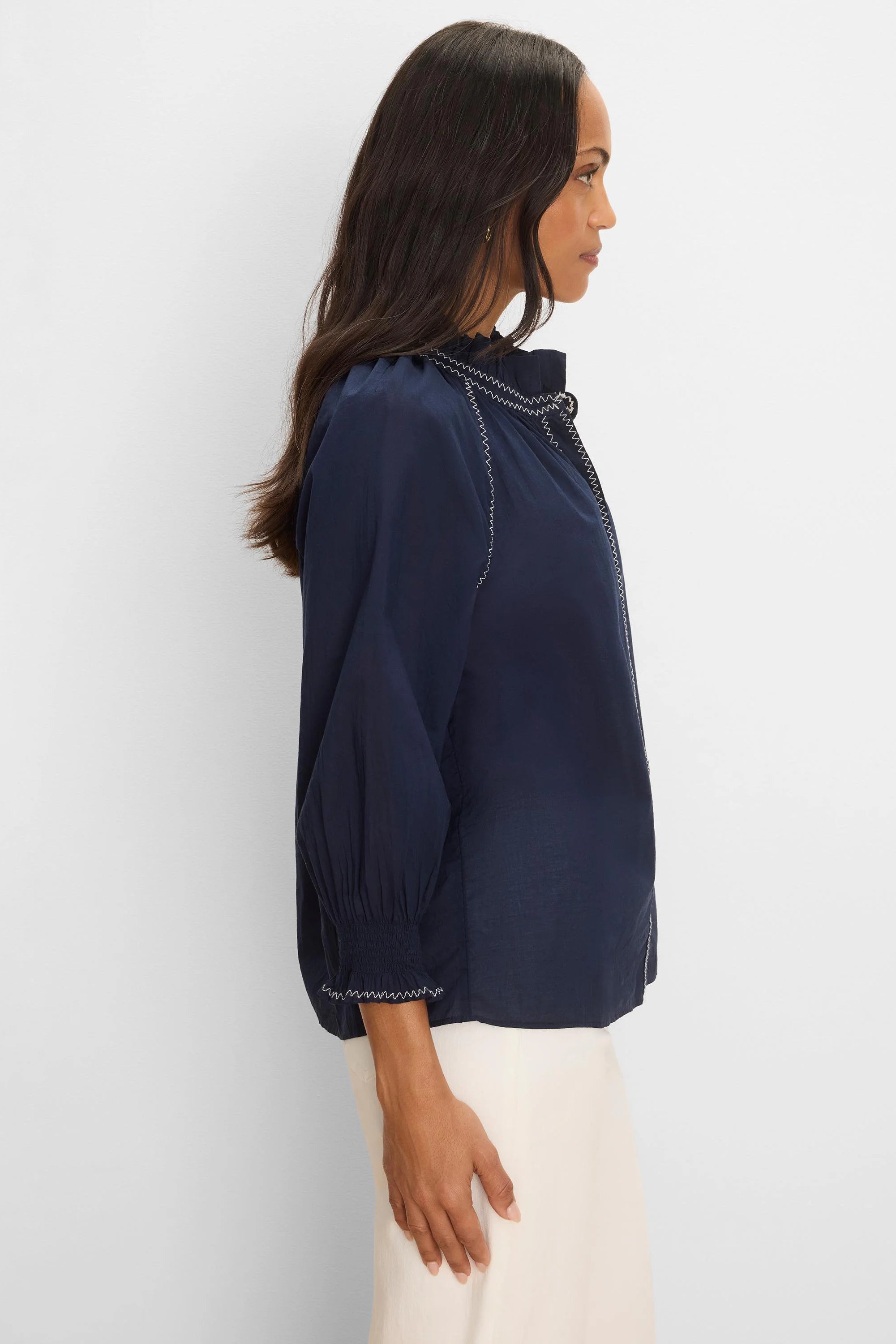 Navy crinkle shirt with white zig-zag stitching on a ruffled collar, raglan seams, and smocked cuffs.