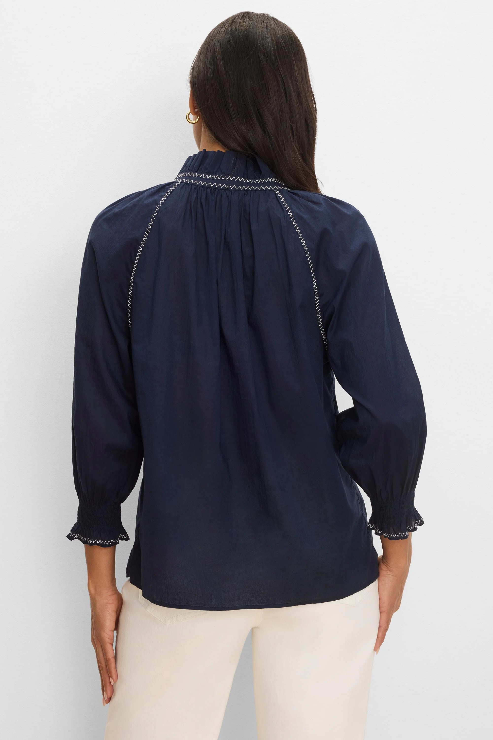 Navy blue crinkle shirt, back view. Features white zig-zag stitching on ruffled neckline, shoulder lines, and smocked cuffs.