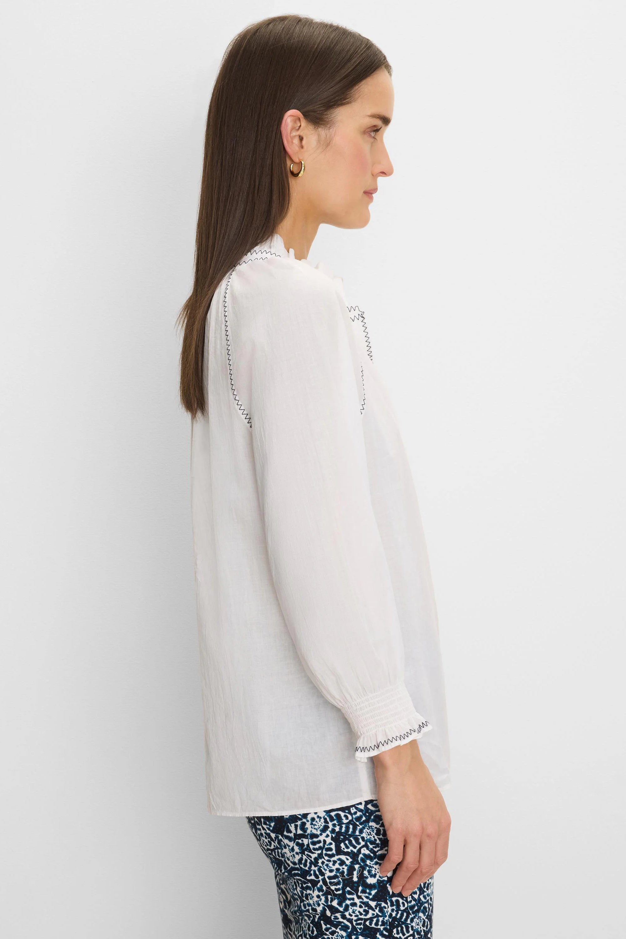 White crinkle cotton shirt with black zig-zag stitching on ruffled collar, shoulders, and smocked cuffs.