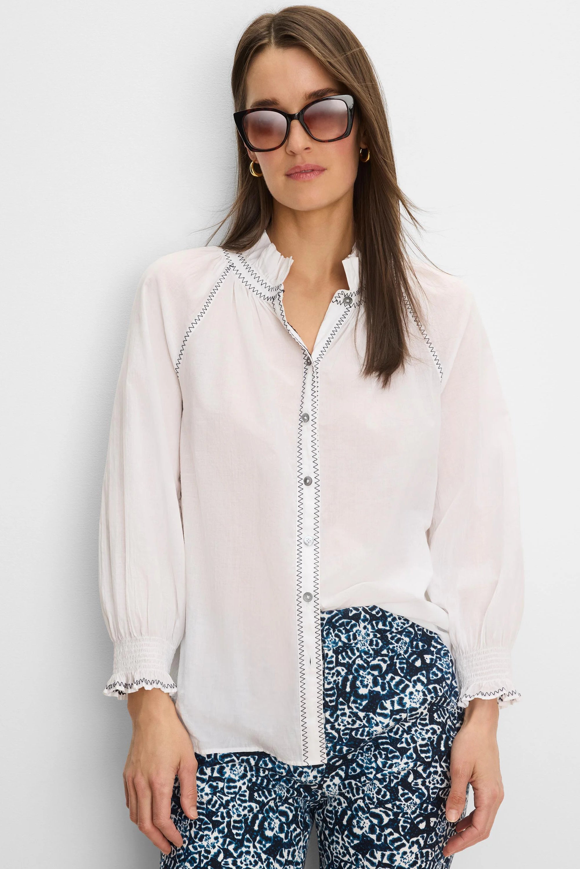 White crinkle shirt with dark zig-zag stitching on the ruffled collar, button placket, and smocked cuffs.