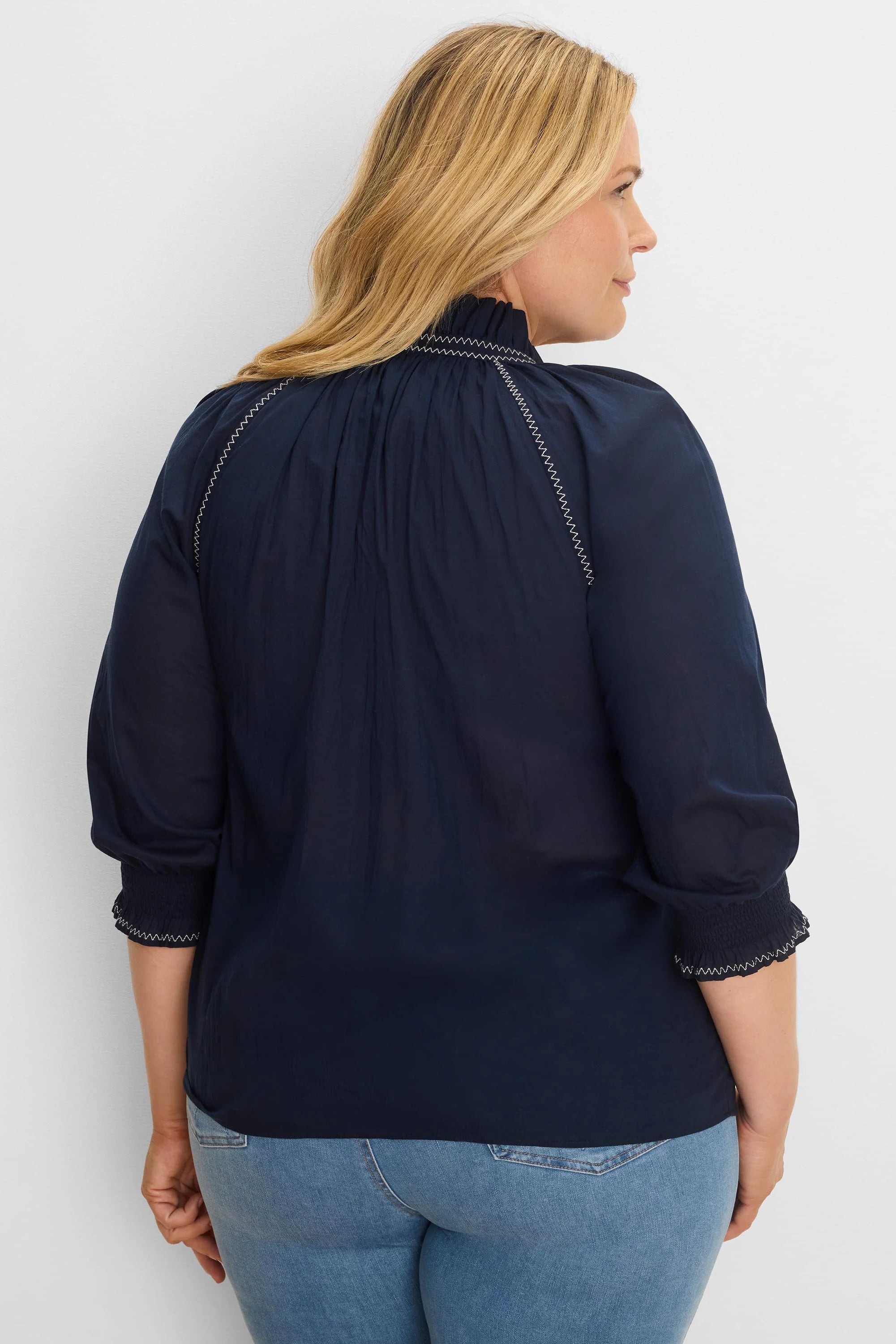 Navy blue cotton crinkle shirt with white zig-zag stitching on shirred mock neck and 3/4 cuffs.
