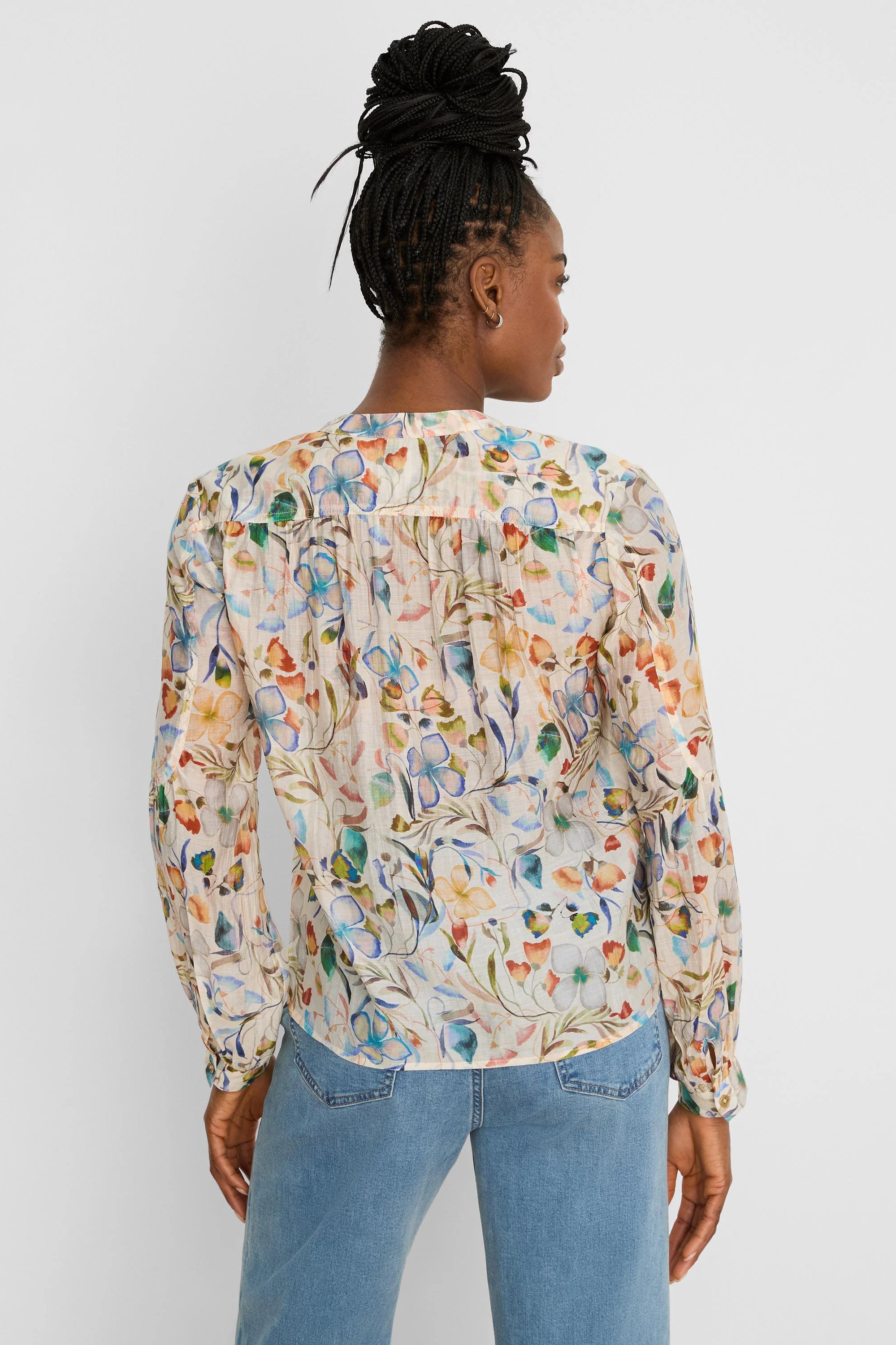 Cream shirt, back view, with multi-color pressed flower print (blues, oranges, greens). Long sleeves, gathered back yoke.