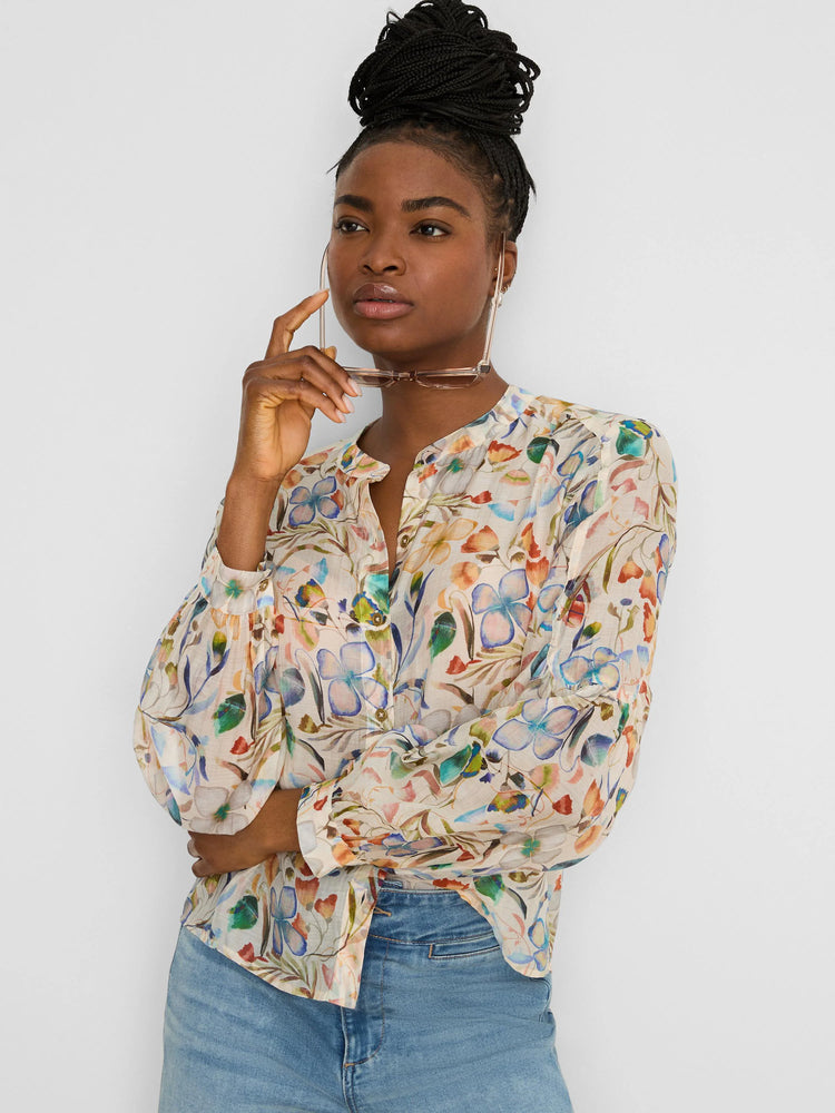 Cream shirt with a multicolored pressed floral print in blues, oranges, and greens. Features a band collar and blouson...