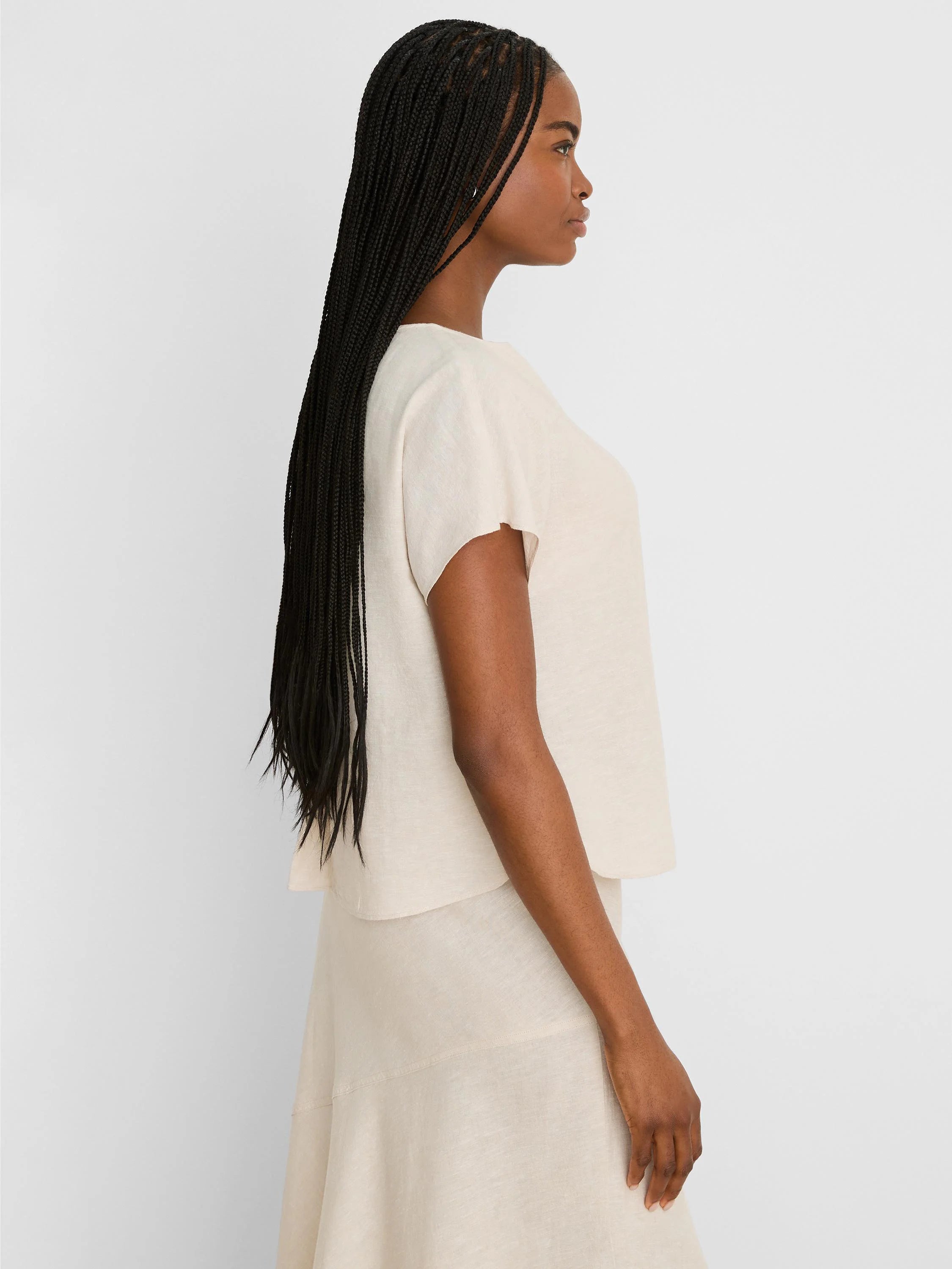 Light beige linen tee with short, wide sleeves, worn by a woman in profile.