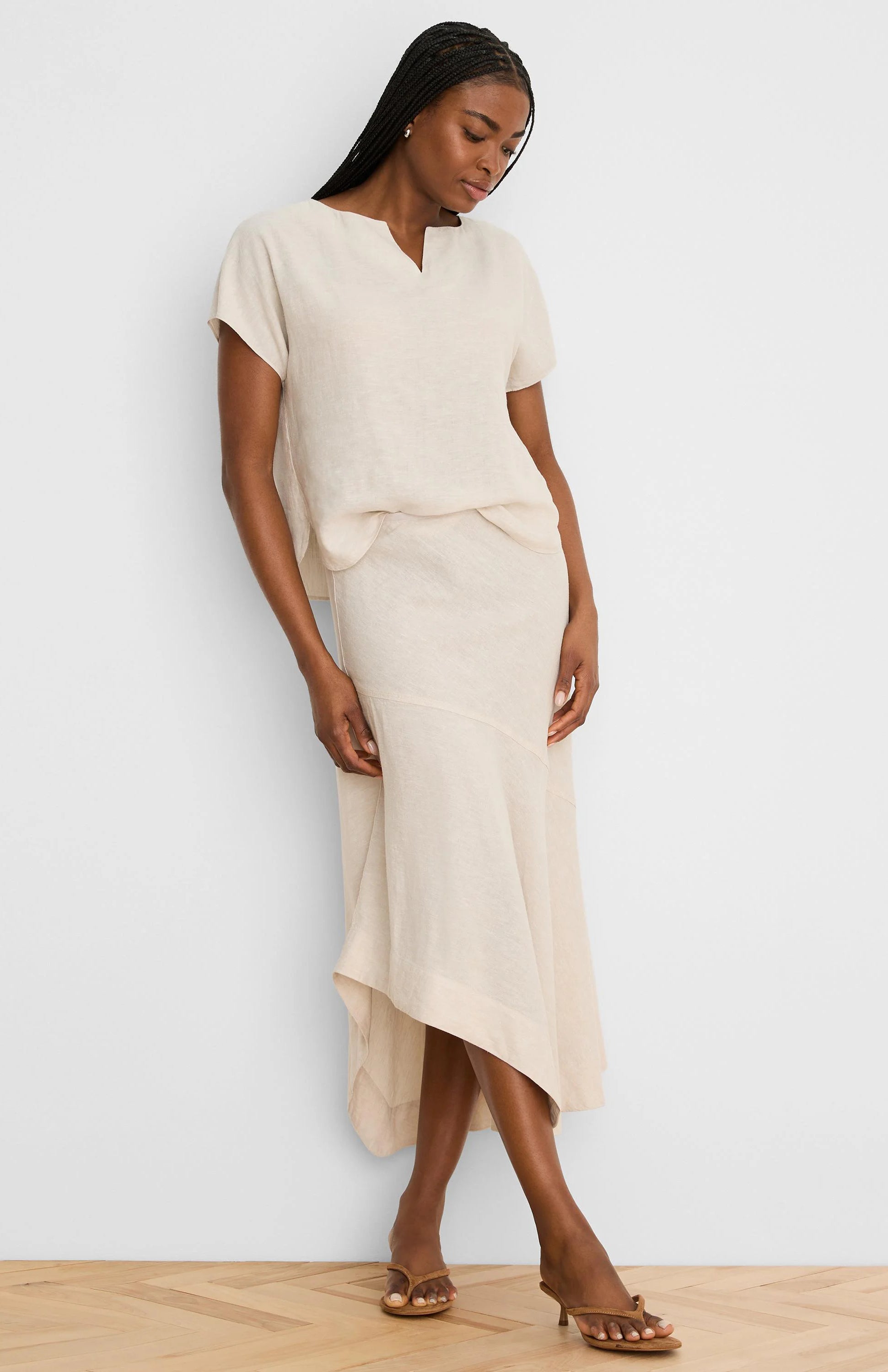 Long light beige linen skirt with an asymmetric hem and flowing drape.