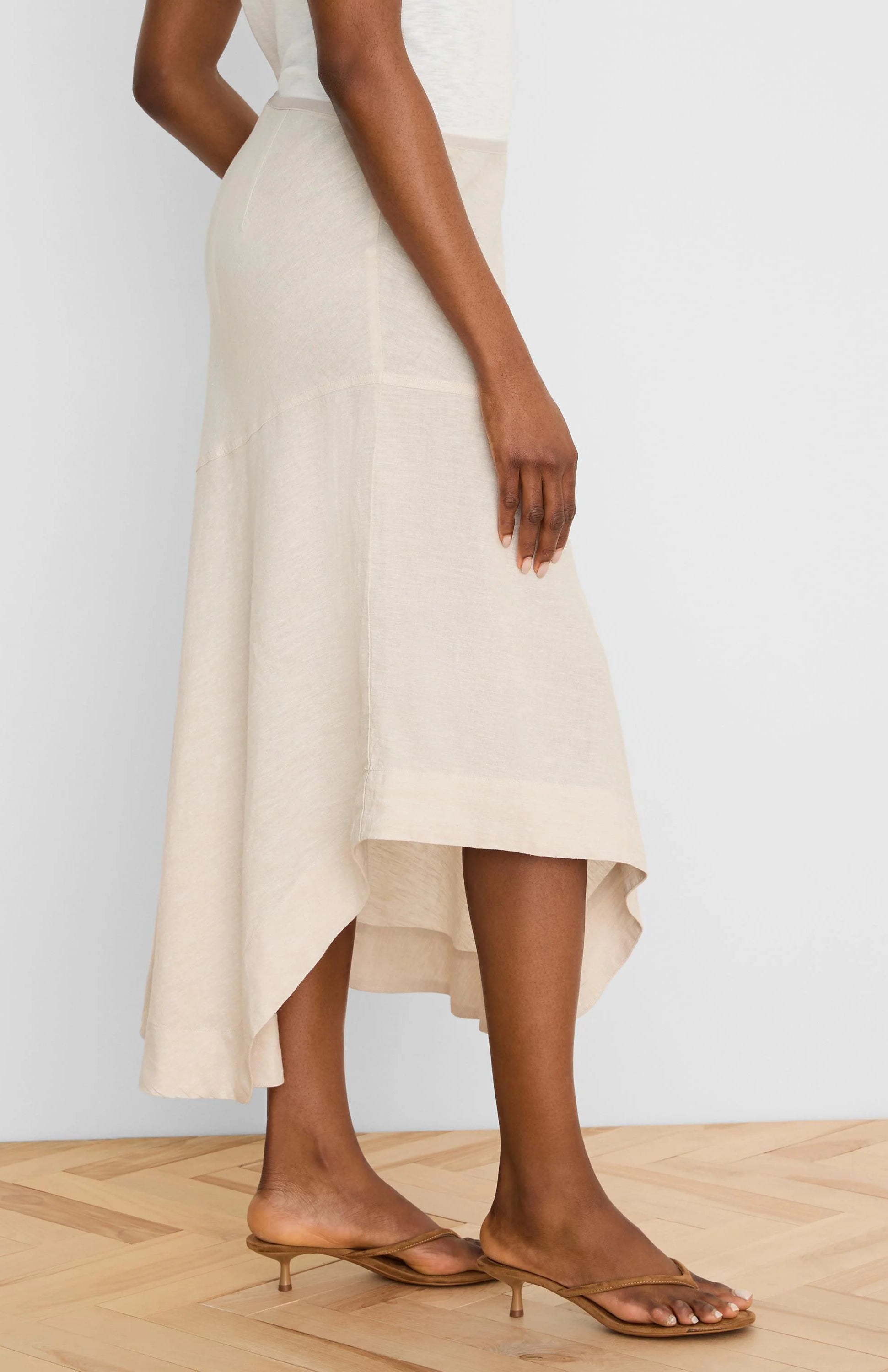 Natural linen midi skirt with a flowing, asymmetrical high-low hem.