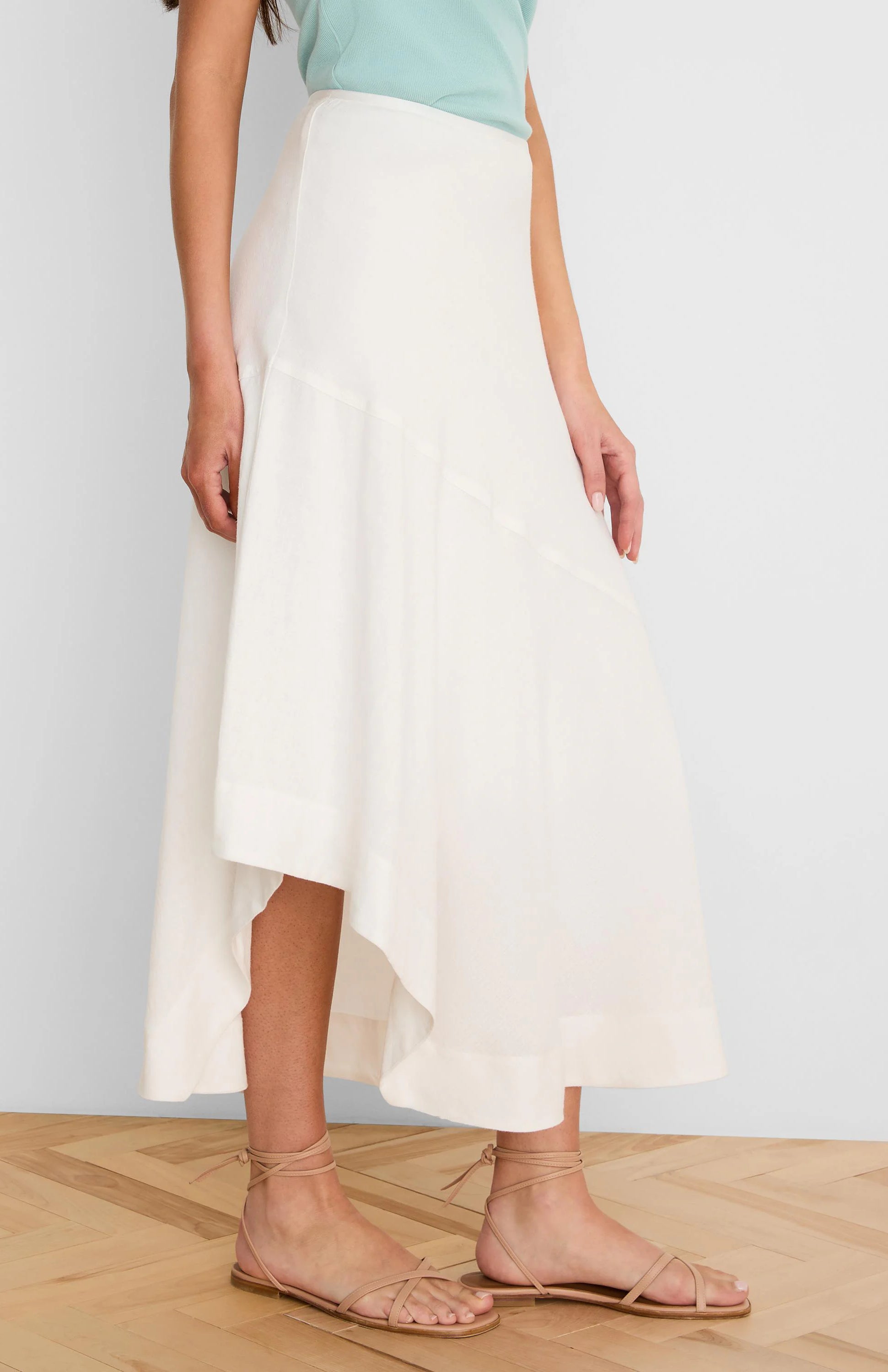 Off-white linen skirt with an asymmetrical, flowing hemline.