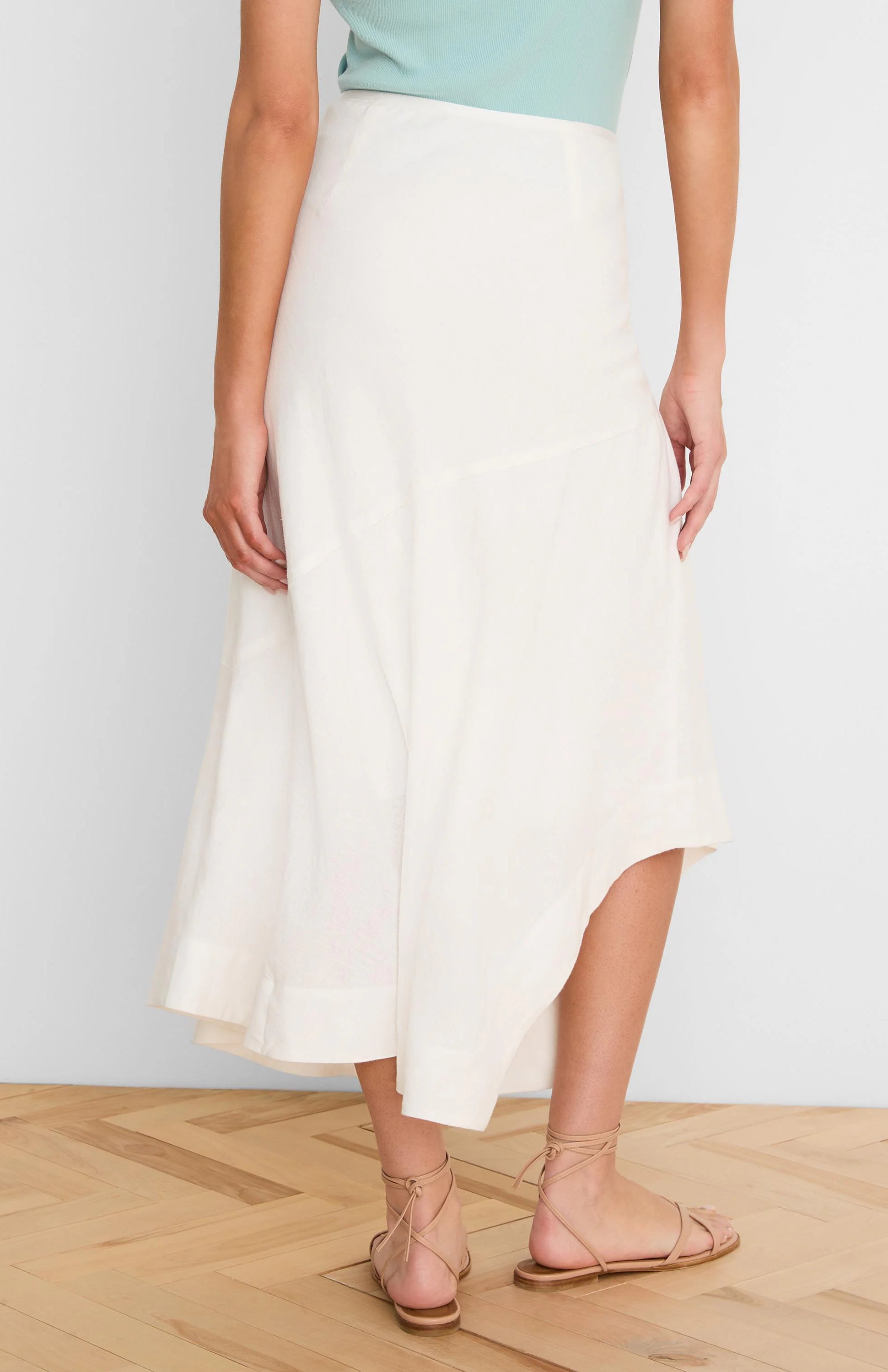 Off-white linen midi skirt with a flowy A-line shape and an asymmetrical hem.