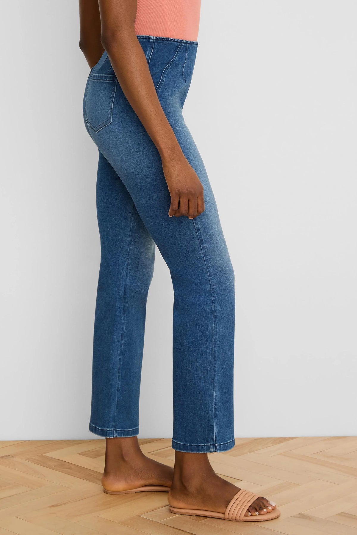 Medium blue ankle bootcut jeans, high-waisted with a structured waistband and diagonal seams.