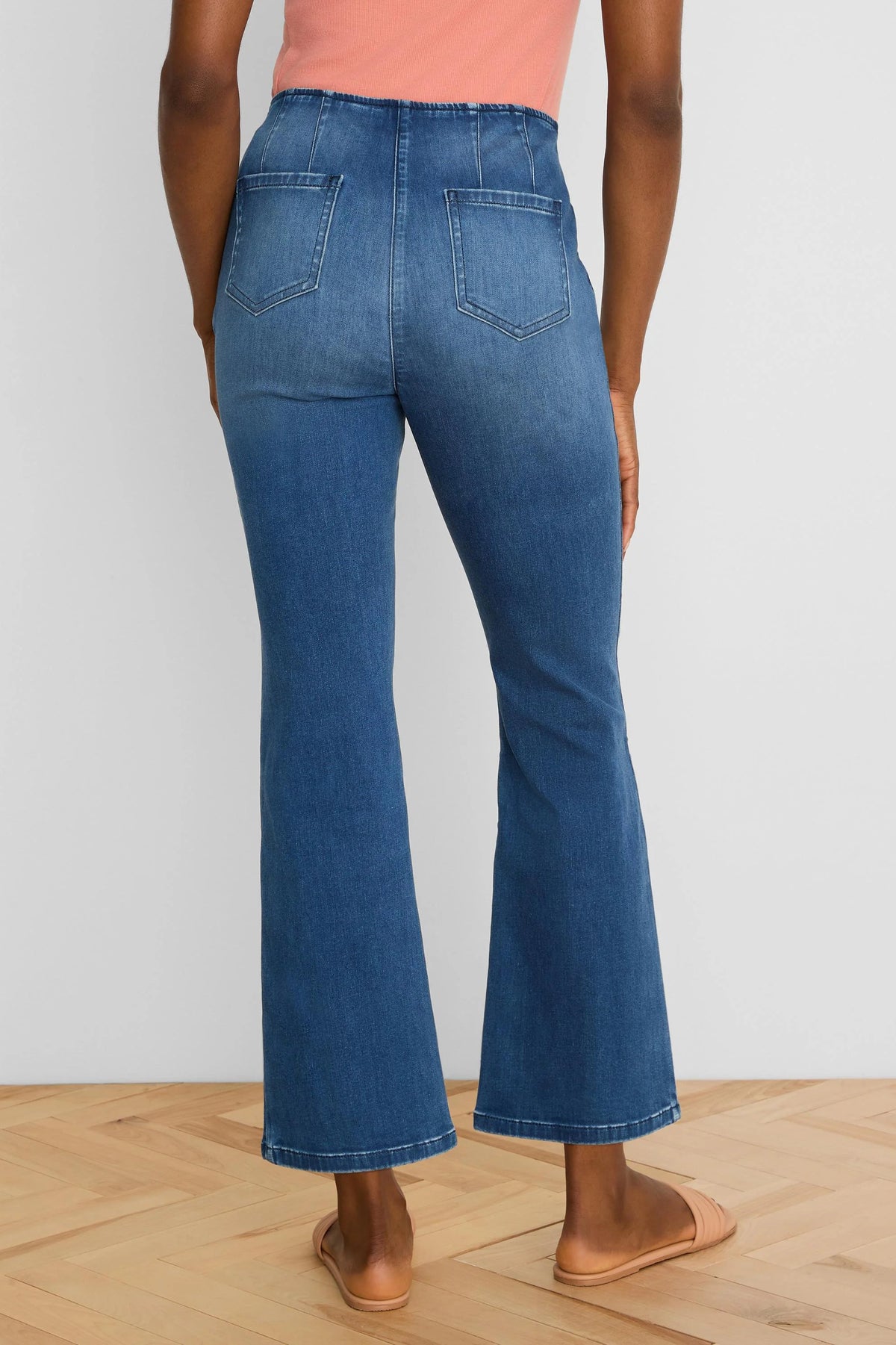 Dark blue, high-waisted bootcut ankle jeans, shown from the back, featuring two back pockets and vertical seams.