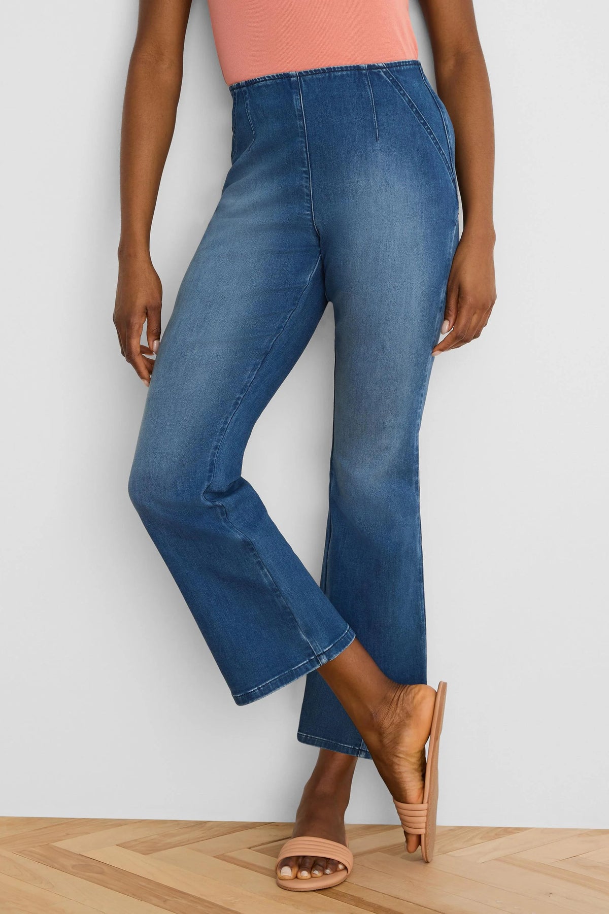 Medium blue ankle bootcut jeans. High-waisted with prominent front vertical seams.