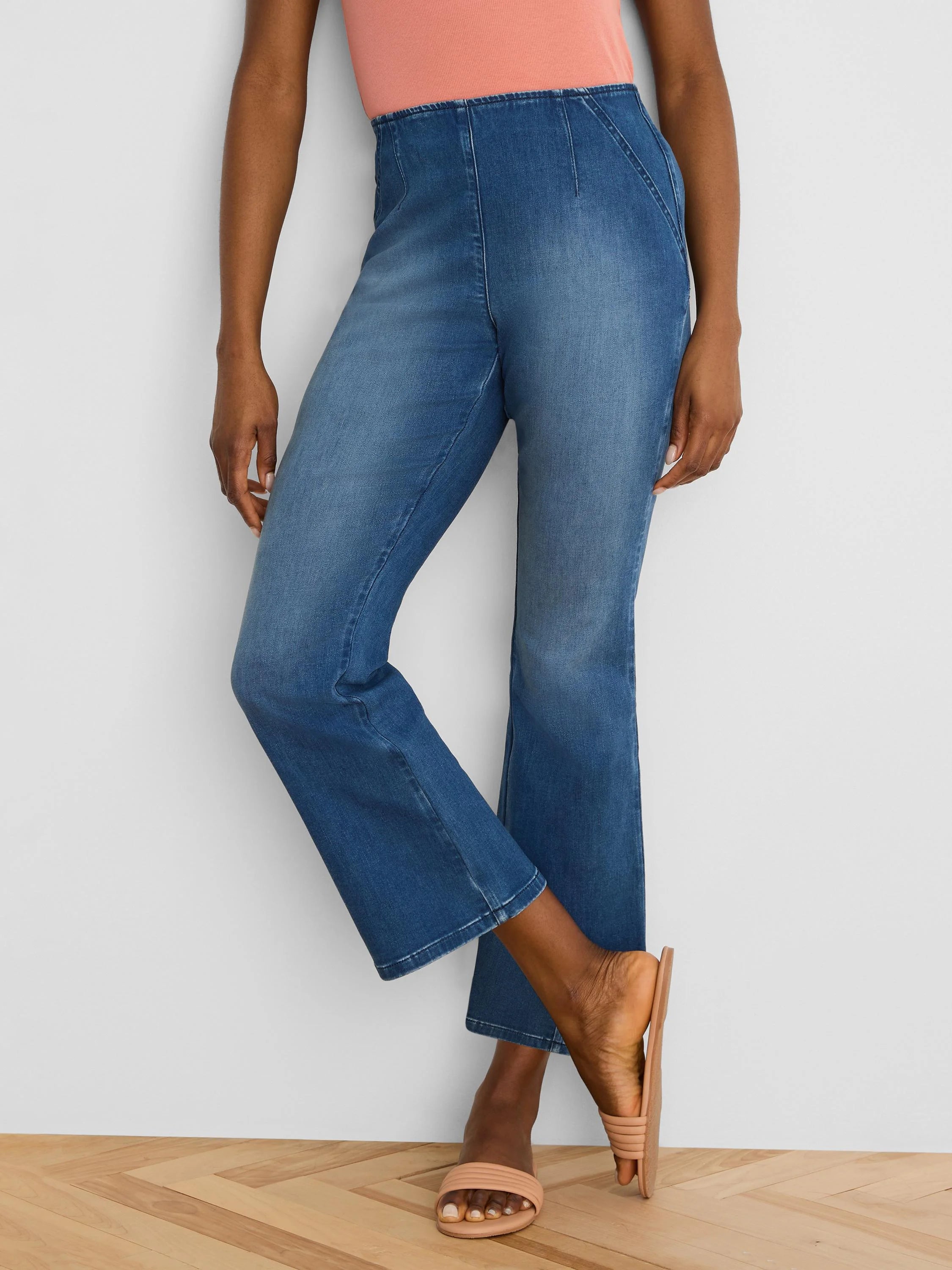 Medium blue ankle bootcut jeans. High-waisted with prominent front vertical seams.