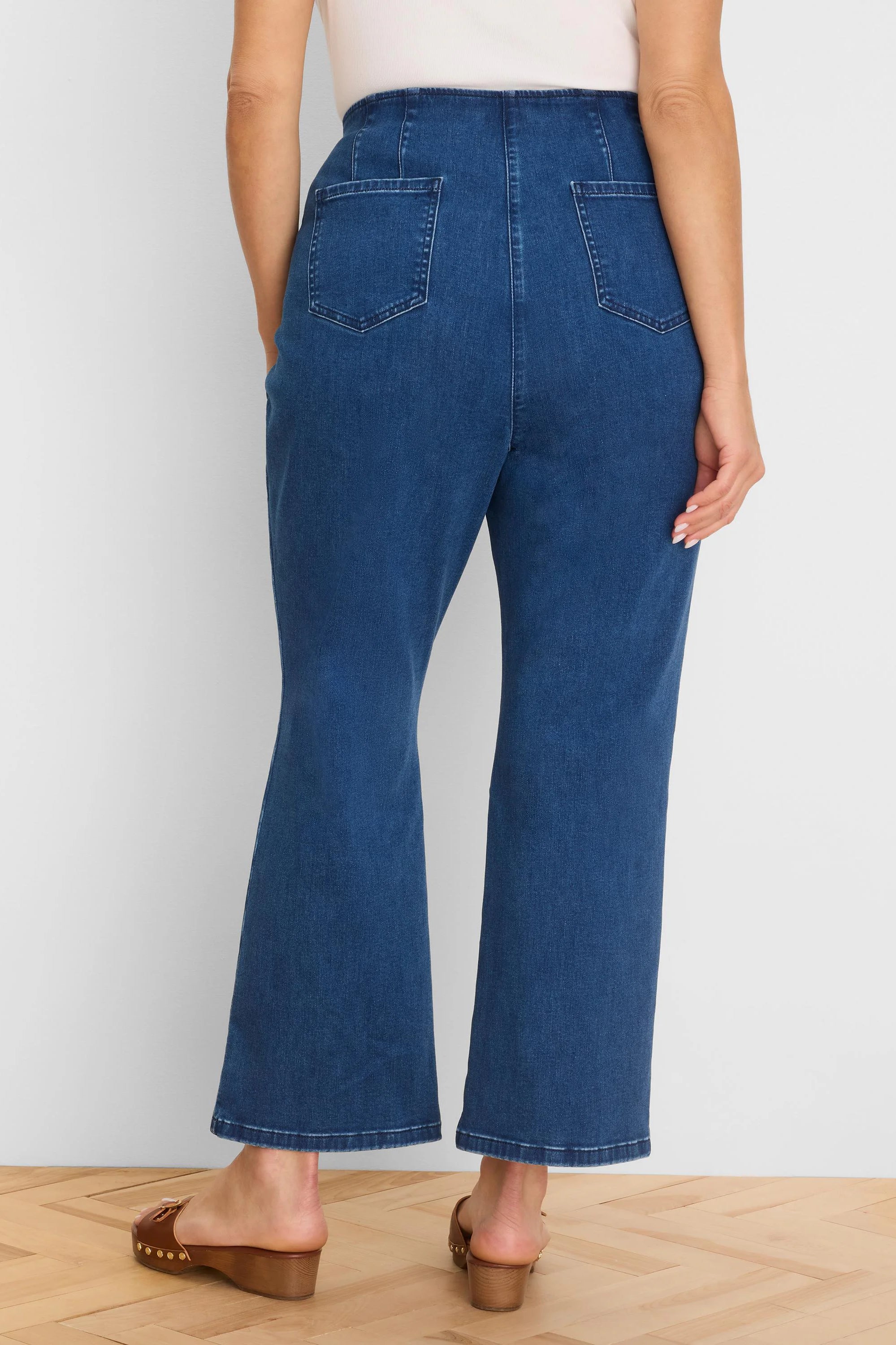 Dark blue boot-cut jeans, high-waisted, with a wide waistband and two back patch pockets, shown from behind.