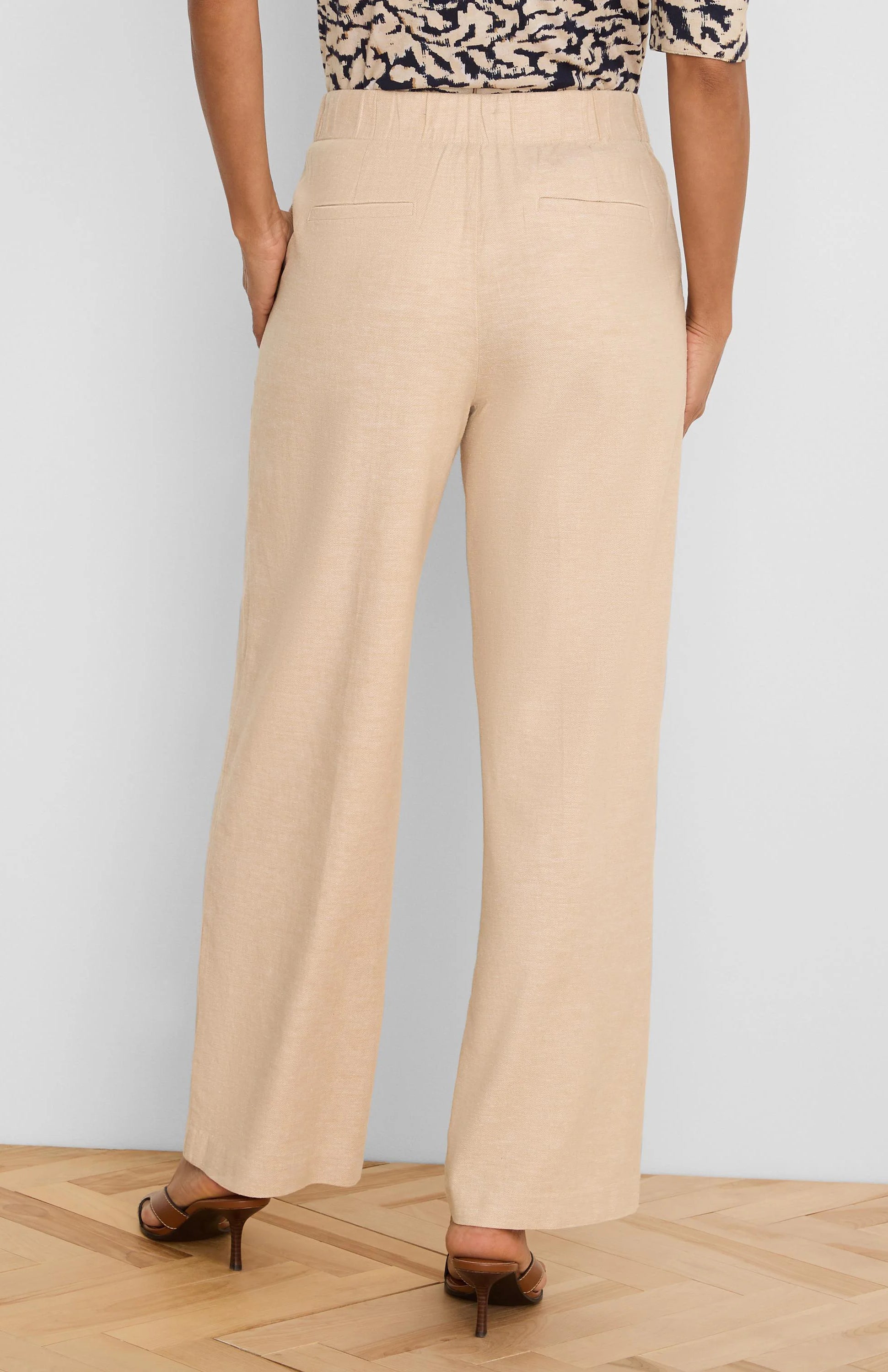 Light beige wide-leg linen pants, back view. Features an elastic waist and two rear welt pockets.