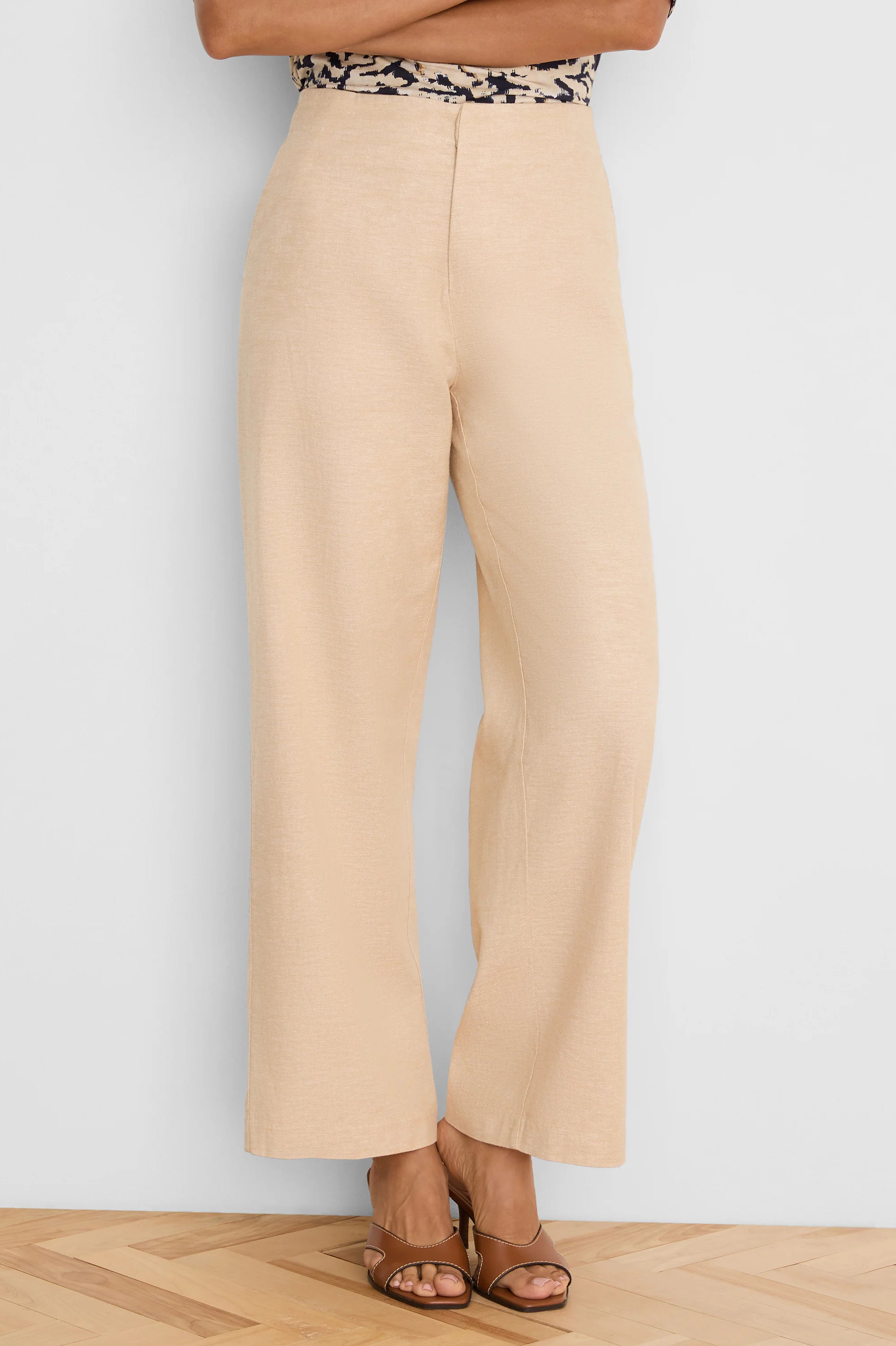 Light beige wide-leg pants, high-waisted, with visible linen texture, falling to the ankles.