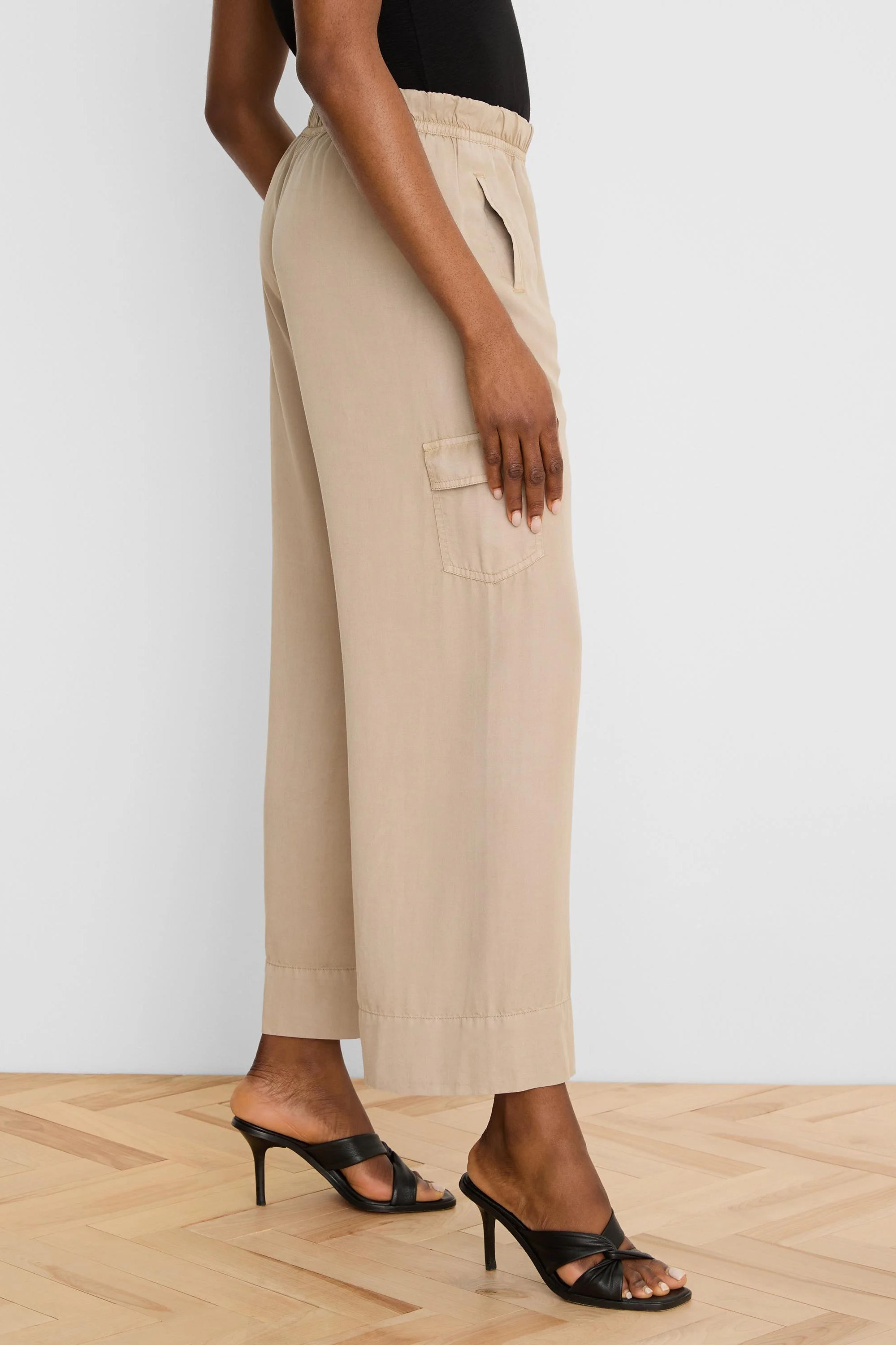 Beige wide-leg drapey cargo ankle pants with an elastic waist and side flap pocket.