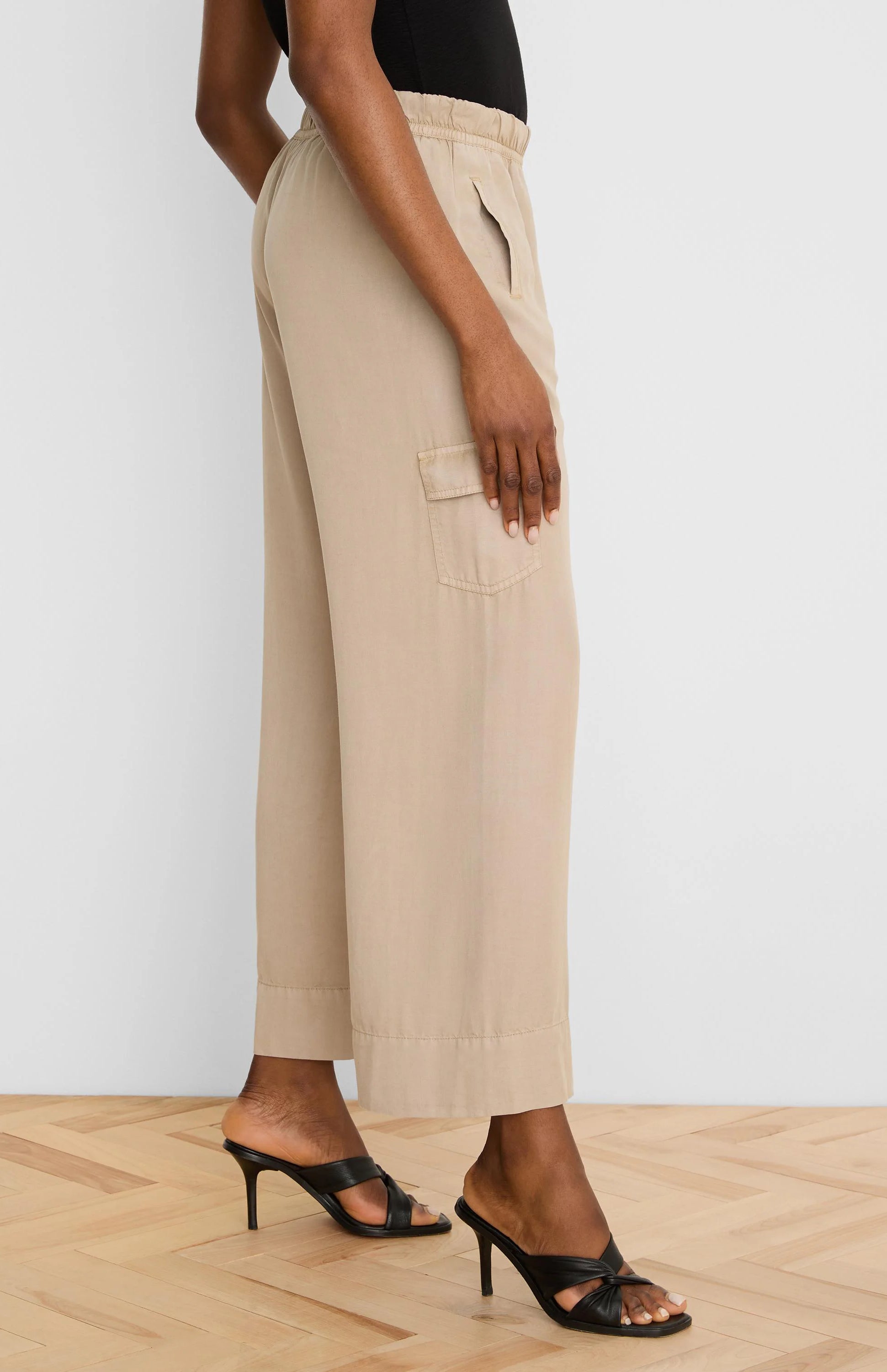Beige wide-leg drapey cargo ankle pants with an elastic waist and side flap pocket.
