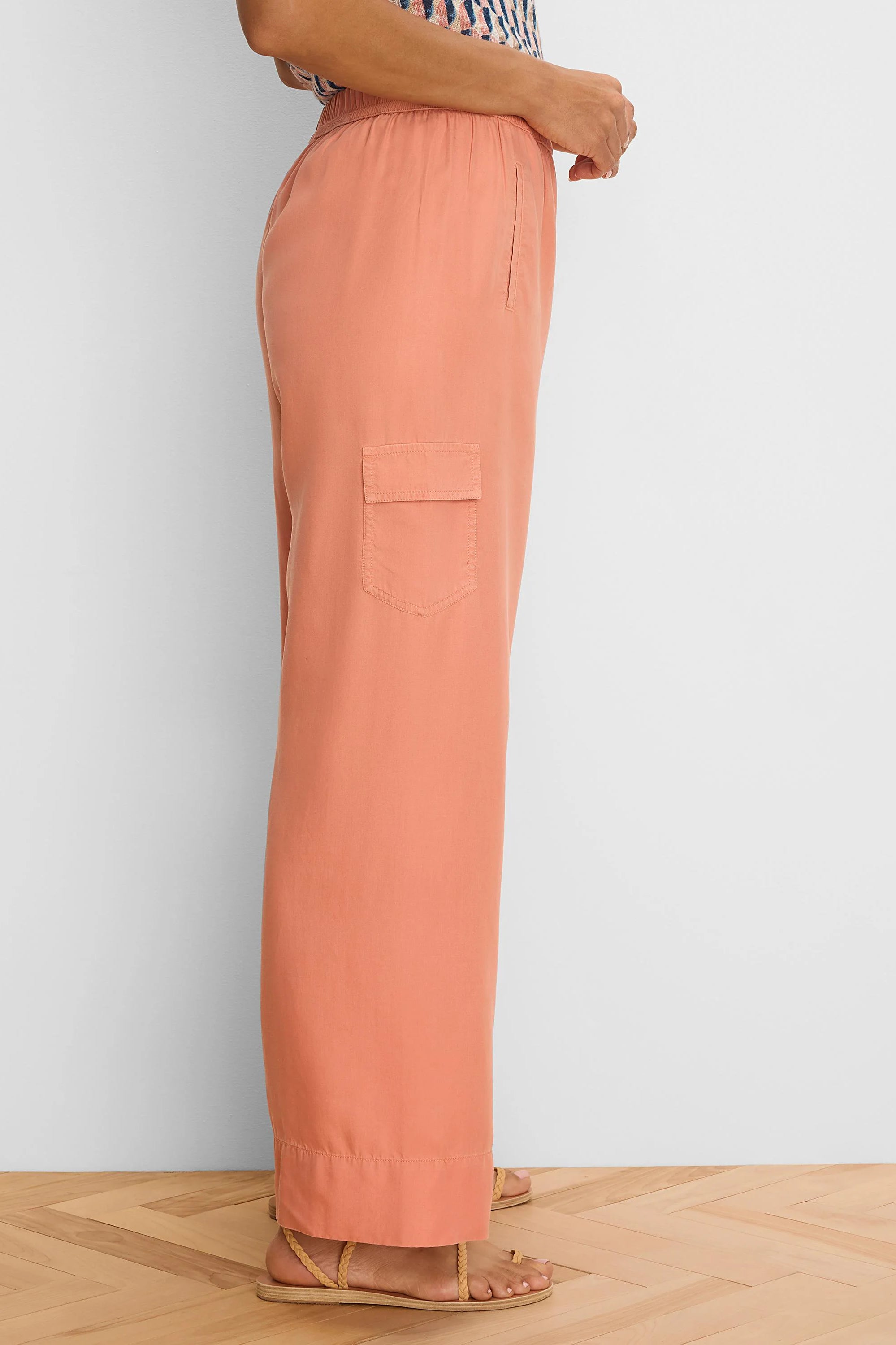 Peachy-orange wide leg drapey cargo ankle pants. Features an elastic waist, side slit pocket, and flap cargo pocket.