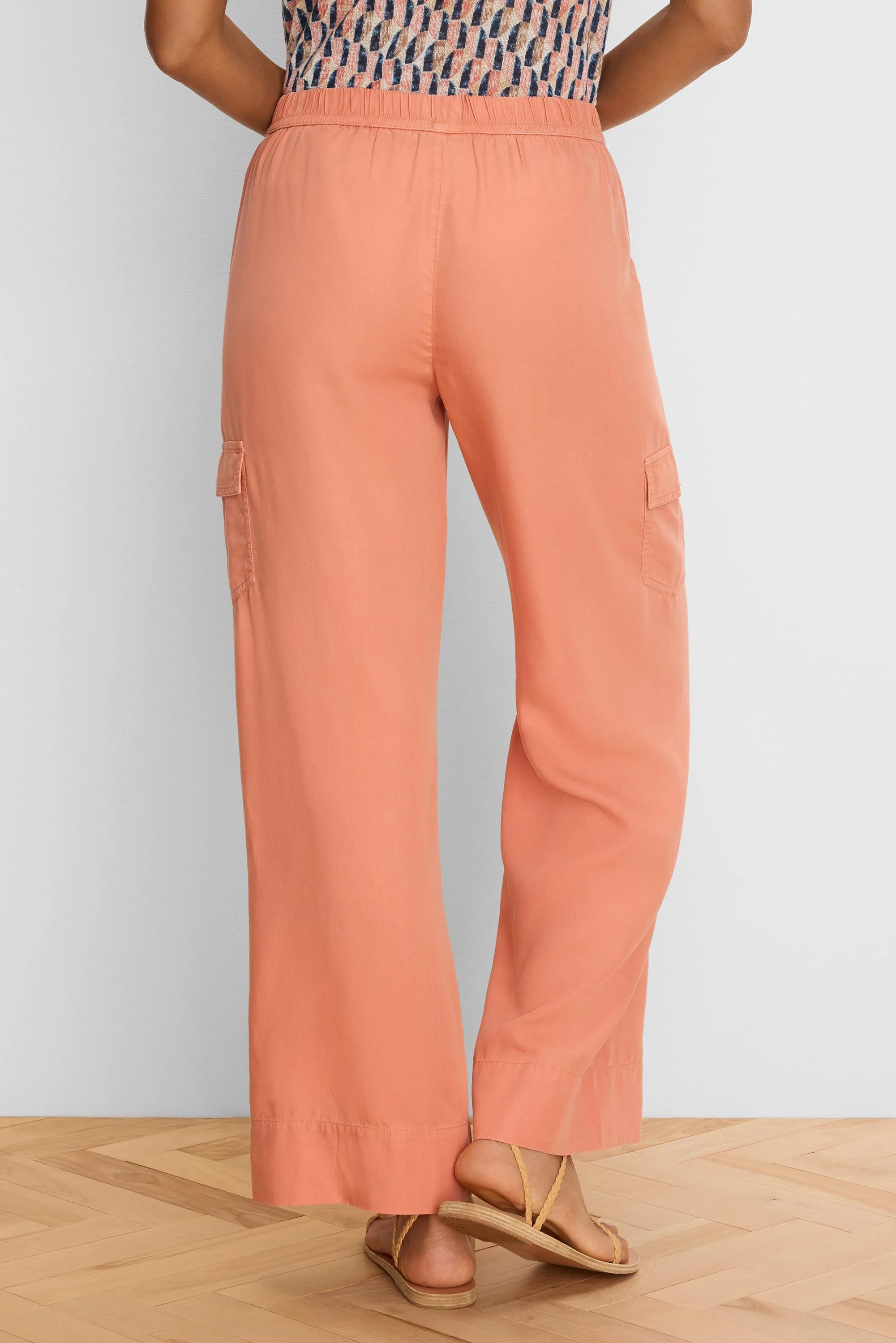 Peach wide leg drapey cargo ankle pants with side pockets and elastic waist, viewed from the back.